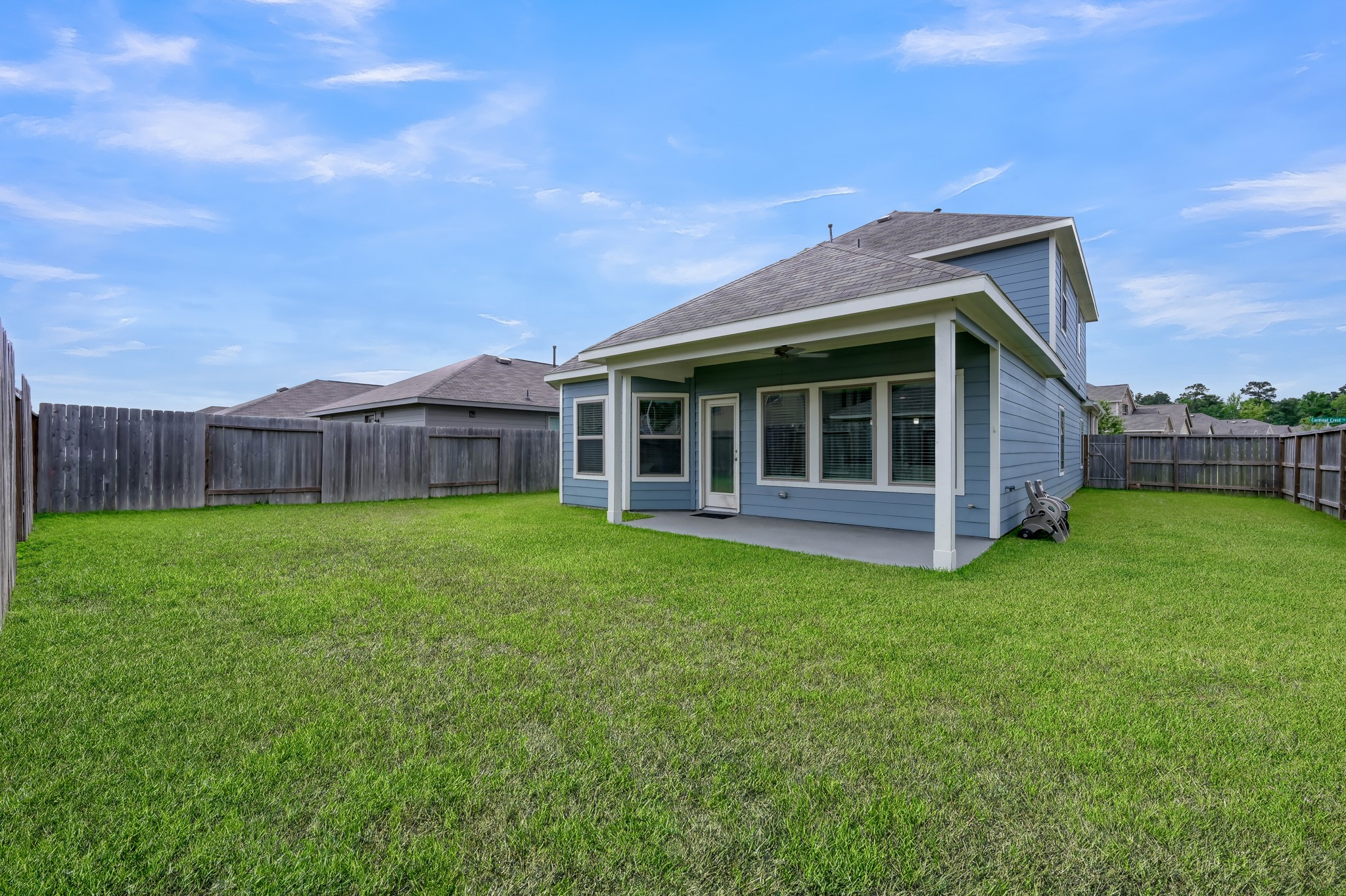 This photo showcases a spacious backyard with a well-maintained lawn, a covered patio area, and a fenced perimeter, providing privacy and ample outdoor space for activities.