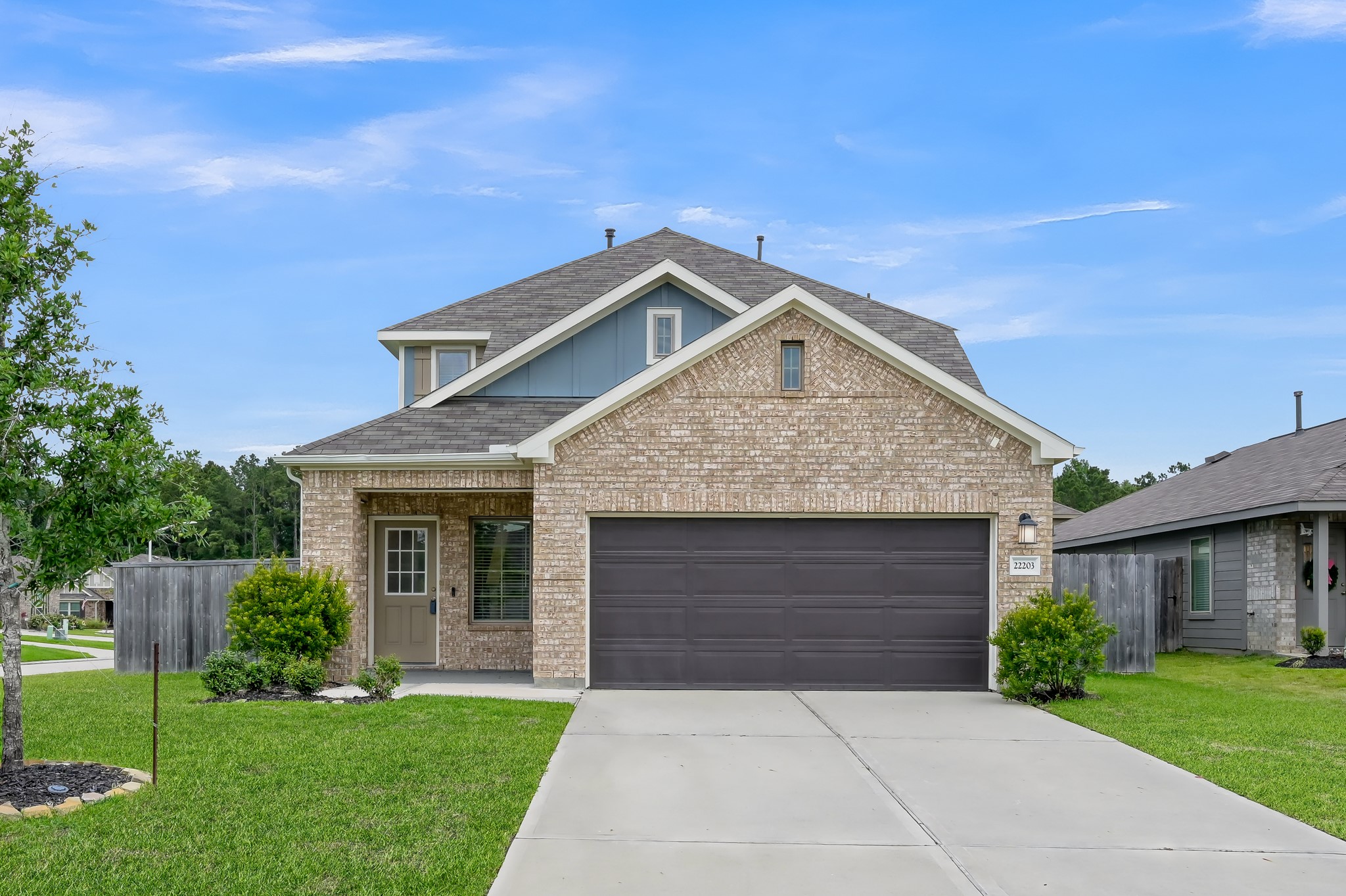 A modern two-story brick house with a two-car garage and a neatly maintained front yard. The home has a welcoming porch and is situated in a suburban neighborhood.