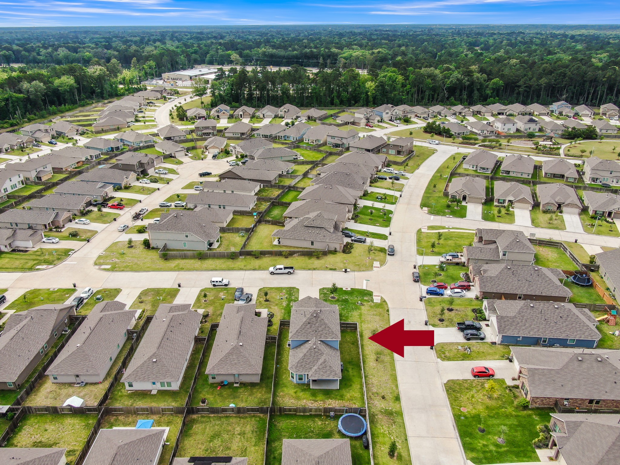 This aerial photo shows a suburban neighborhood with neatly arranged single-family homes. The highlighted house has a fenced backyard, nearby green spaces, and is situated in a quiet, well-maintained community.