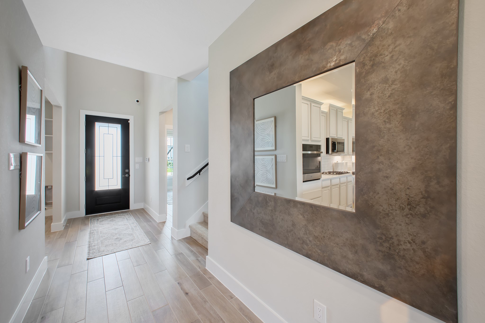 As you step into the threshold of this luxurious home, you'll soon be welcomed by an elegant glass door. Inside, soaring ceilings amplify the spaciousness, while the refined wood-look tile flooring and oversized baseboards exude sophistication and charm.