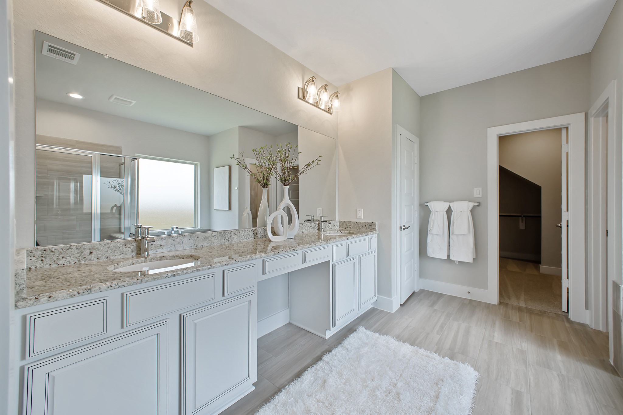 Elevate your daily routine at the elegant vanity, now equipped with double sinks, light countertops, modern hardware, and beautiful vanity lights.