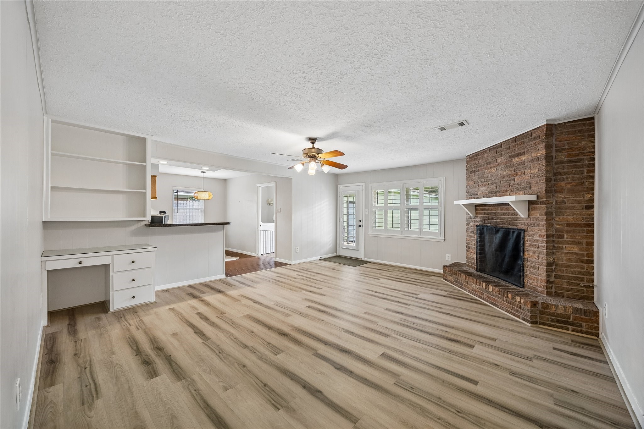 Great view of the den - notice the plantation shutters . The kitchen and breakfast rooms are to the left.  Built in desk and shelves makes a great study area.