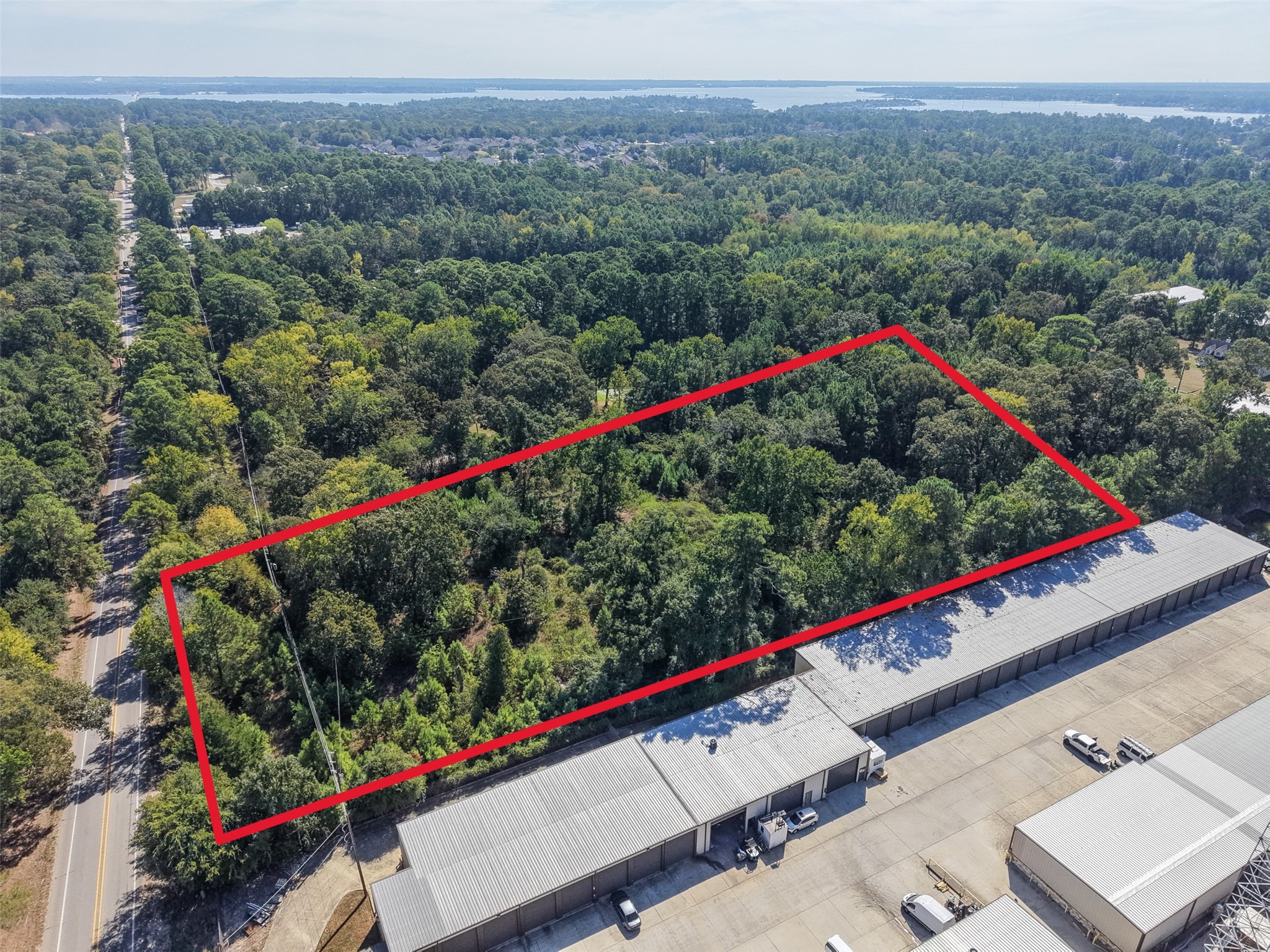 Clearly defined aerial view highlighting the property's configuration, mature tree coverage, and proximity to neighboring commercial improvements. Road frontage and the nearby Lake Conroe area contribute to this tract's investment and development appeal. Clearly defined aerial view highlighting the property's configuration, mature tree coverage, and proximity to neighboring commercial improvements. Road frontage and the nearby Lake Conroe area contribute to this tract's investment and development appeal.