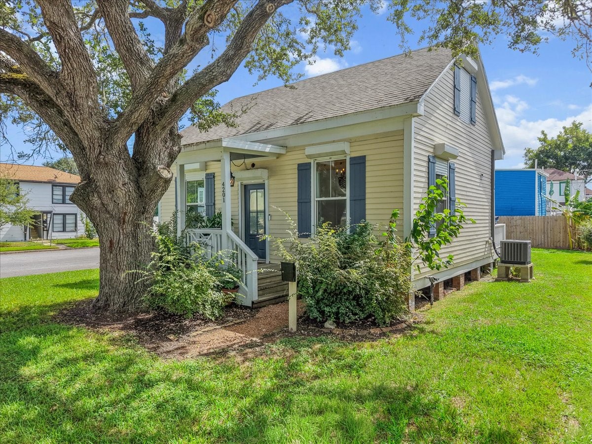 Charming Galveston home with mature shade trees and inviting curb appeal.