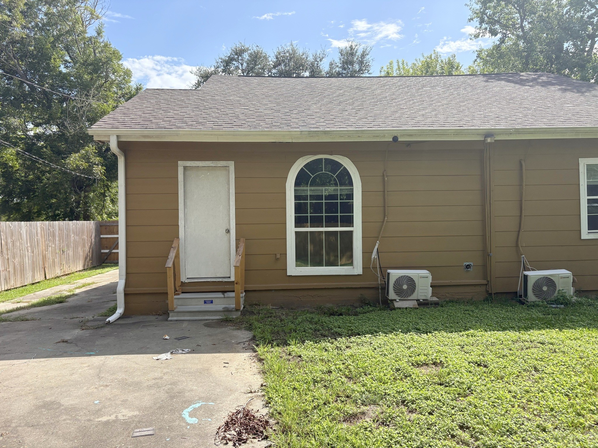 Rear exterior with an arched window, entry steps, and a view of the existing siding.
