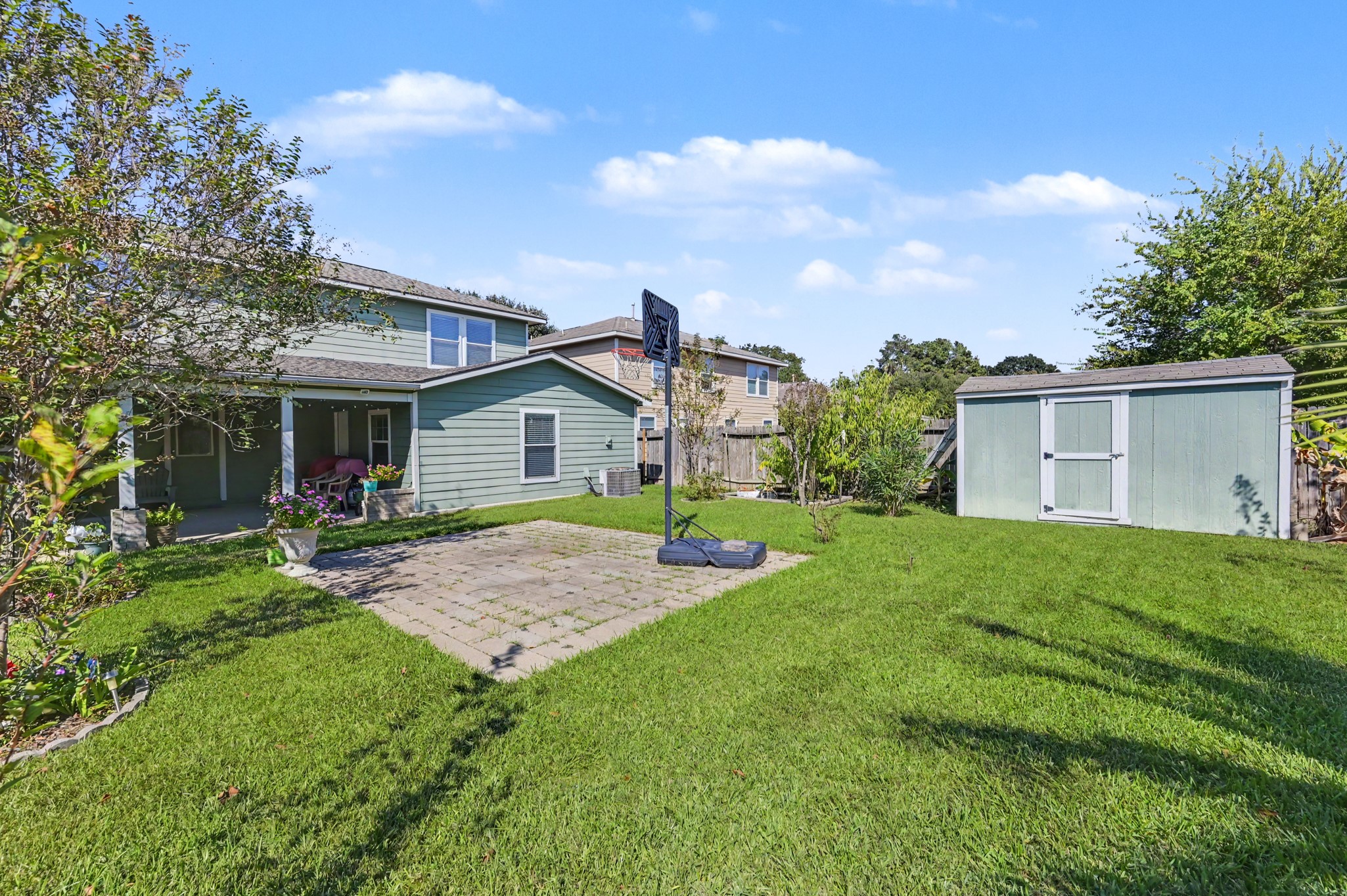 Spacious backyard featuring a well-maintained lawn, cozy patio area, and a practical storage shed, perfect for outdoor activities and relaxation.