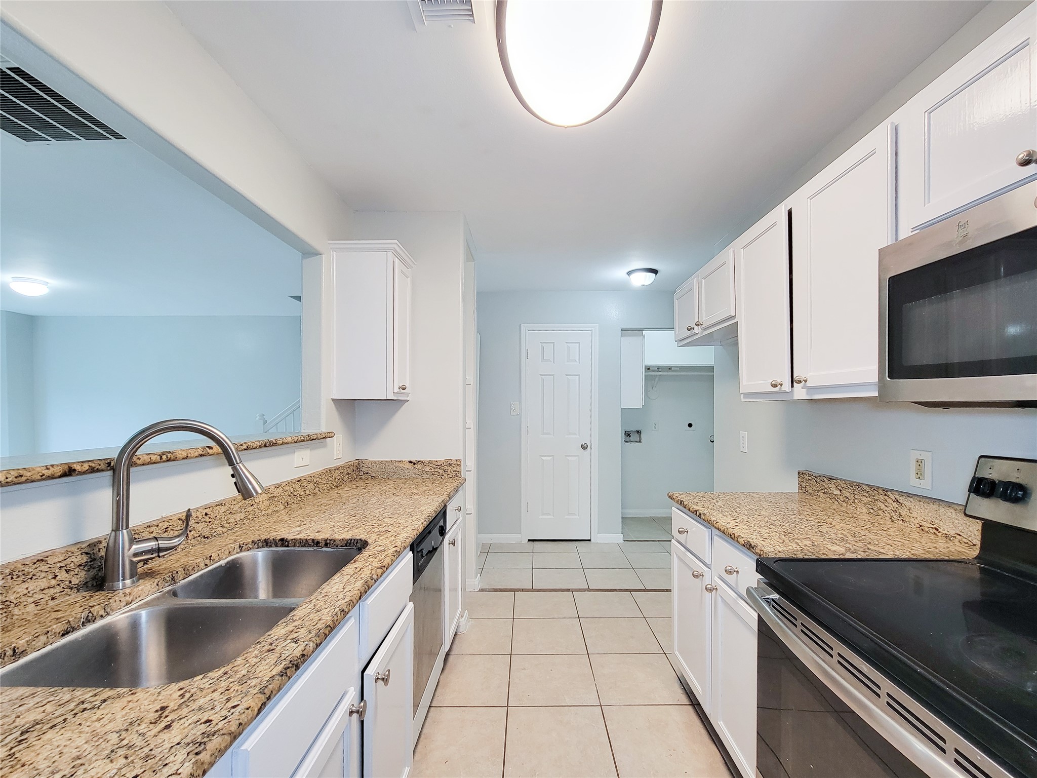 Bright and modern kitchen featuring granite countertops, stainless steel appliances, and ample cabinet space, seamlessly connected to the living area.
