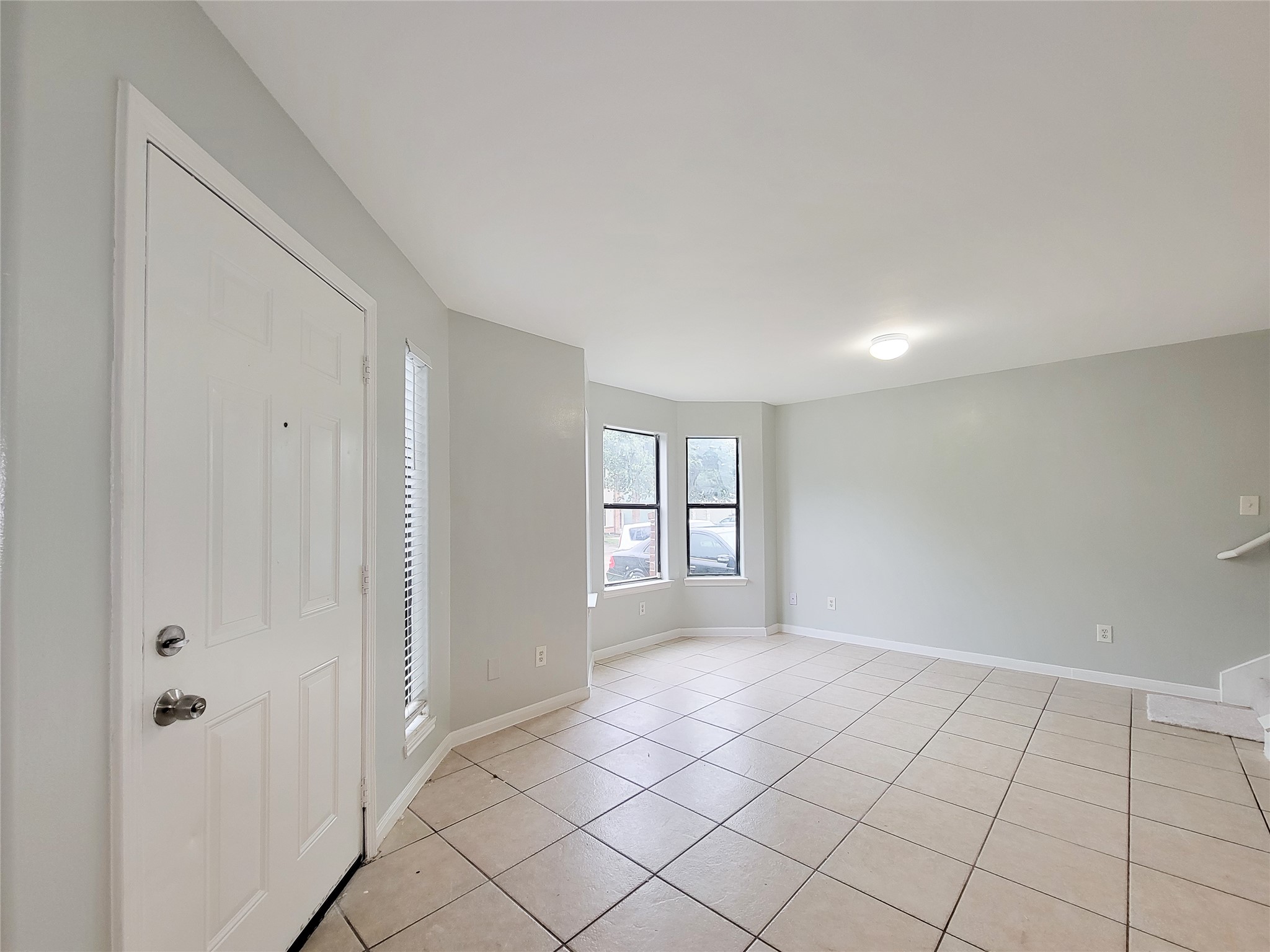 Bright and spacious entryway with tiled flooring, neutral walls, and ample natural light from large windows, creating an inviting atmosphere.