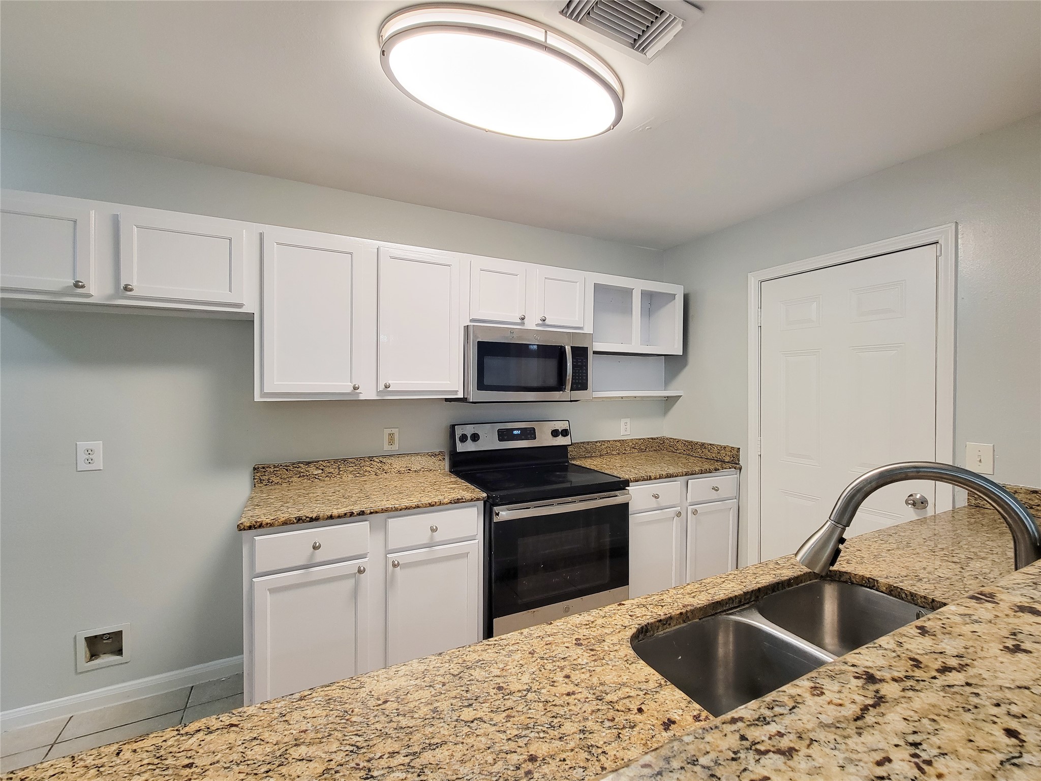 Modern kitchen with sleek granite countertops, stainless steel appliances, and ample white cabinetry for storage.