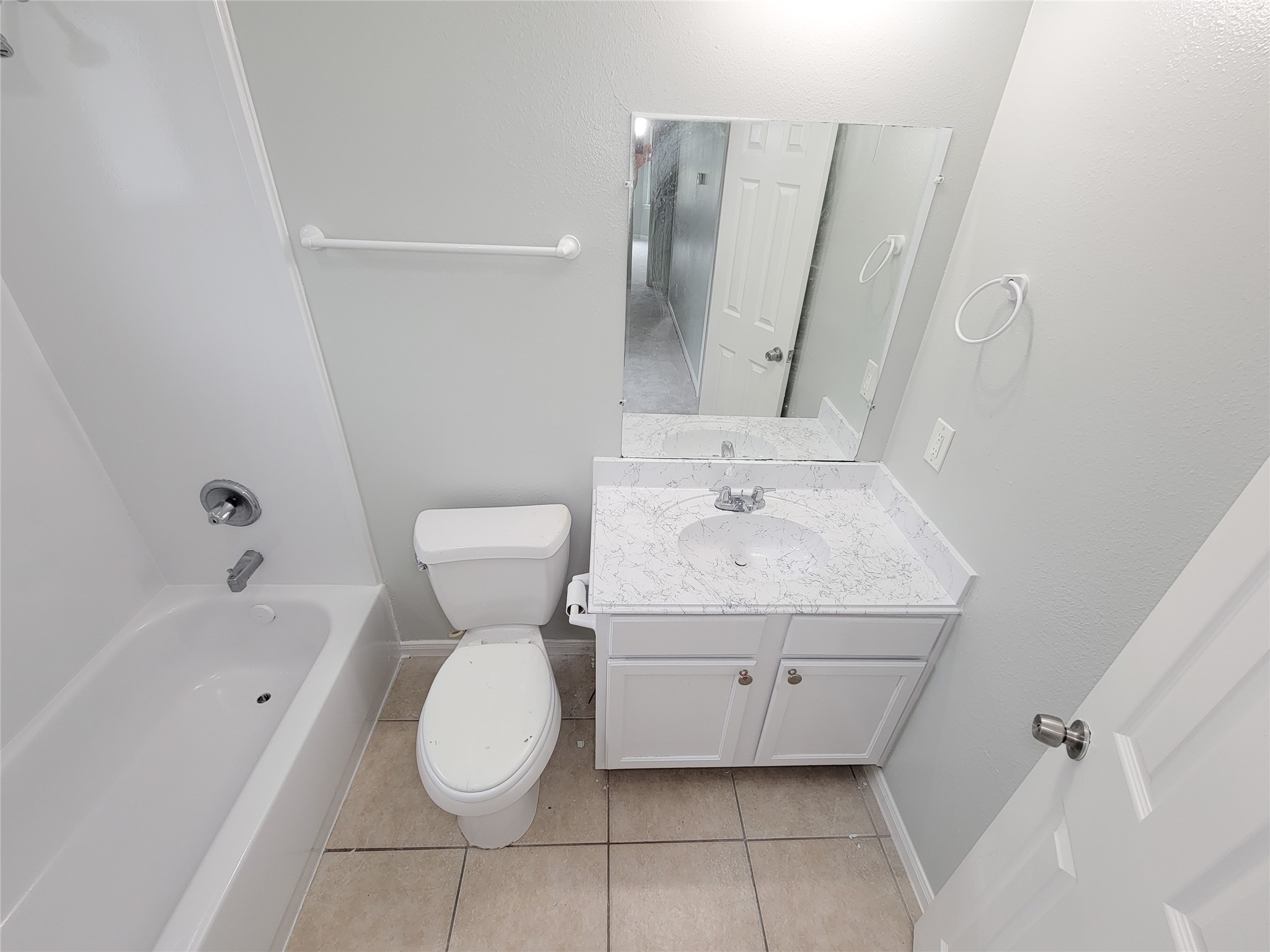 Bright and clean bathroom featuring a modern vanity with marble-style countertop, large mirror, and a full bathtub with shower.