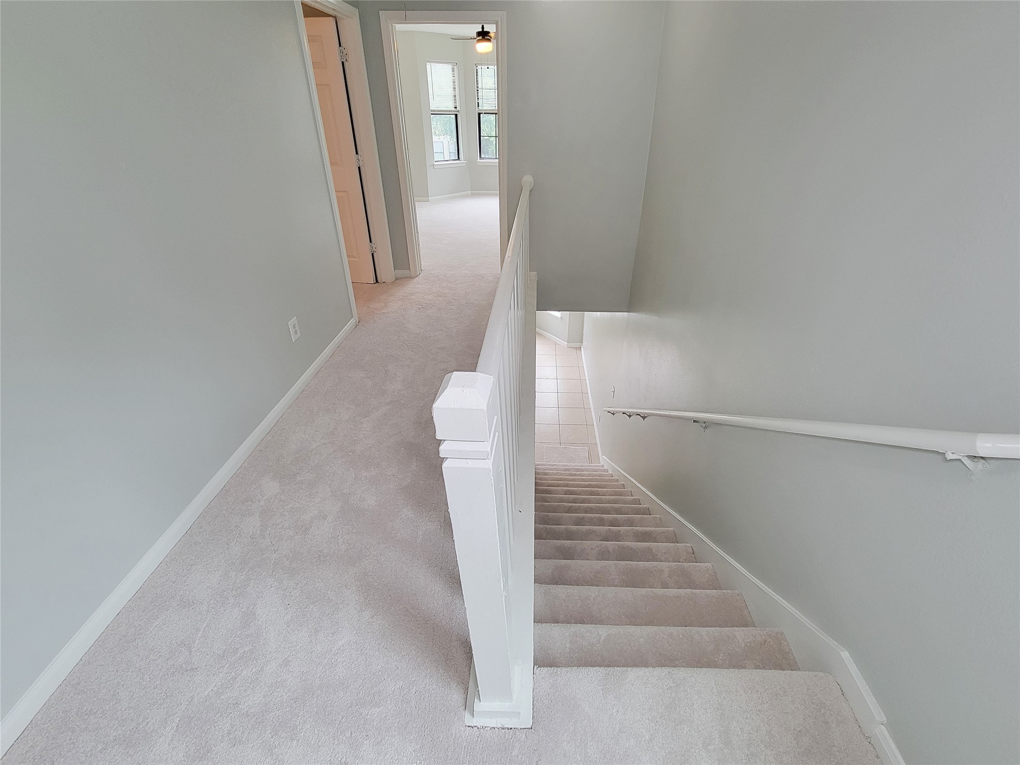 Bright and airy hallway with plush carpeting leads to a spacious room, offering ample natural light through large windows.