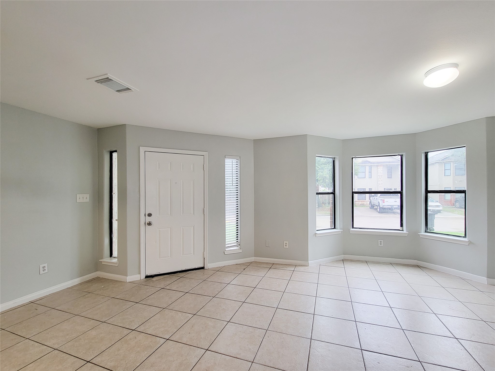 Bright and airy living space with large windows, neutral walls, and tile flooring create a welcoming environment.
