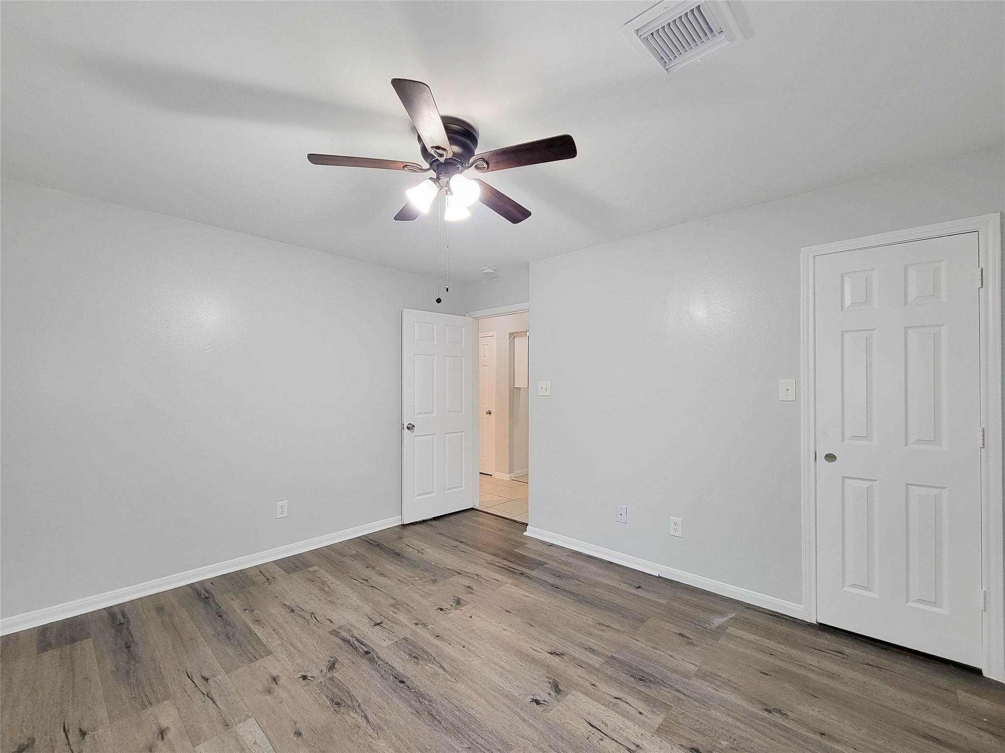 Bright and airy room featuring sleek wood flooring, neutral walls, and a modern ceiling fan, ideal for a cozy living space.