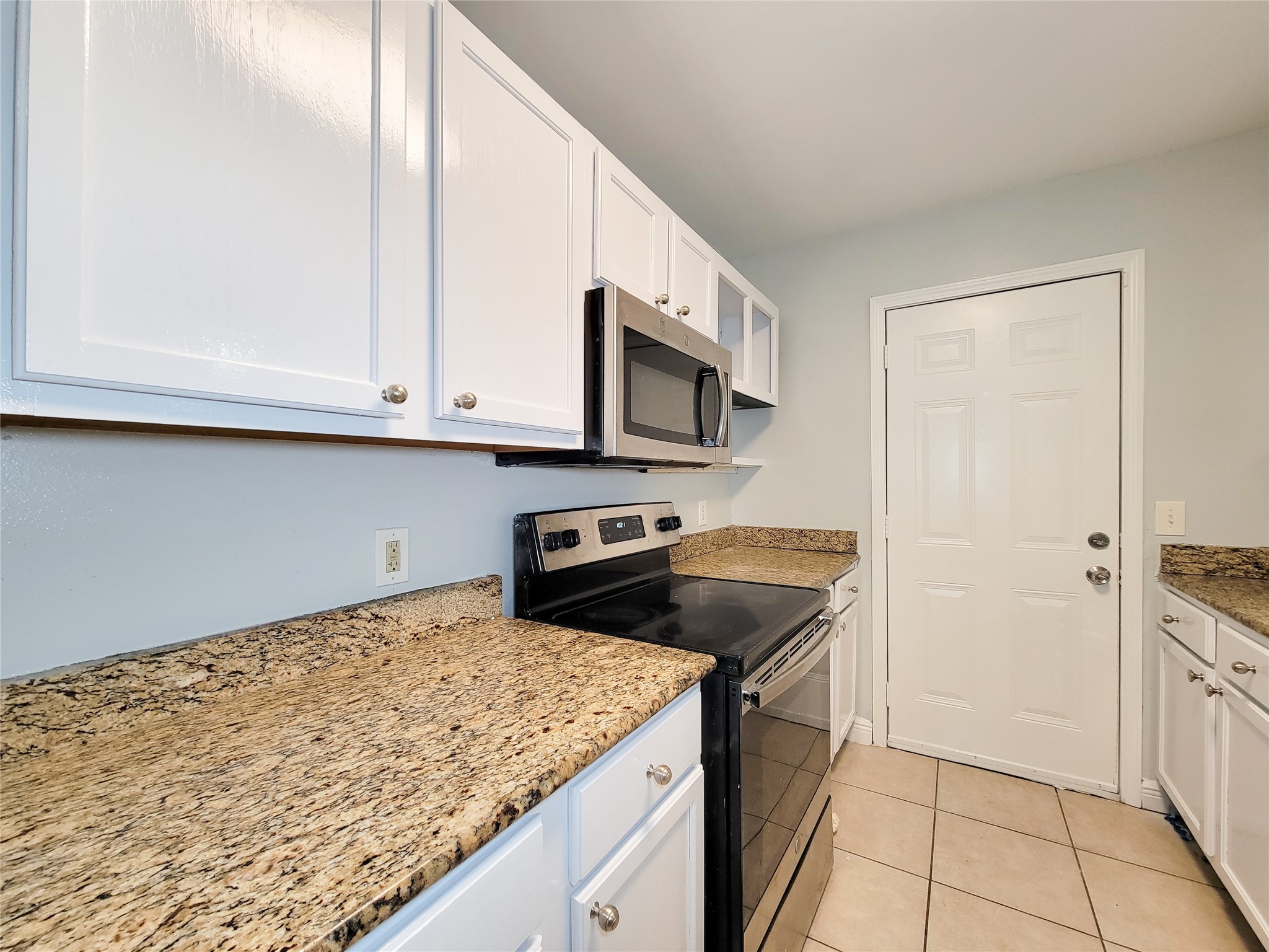 Modern kitchen with sleek granite countertops, stainless steel appliances, and crisp white cabinetry.