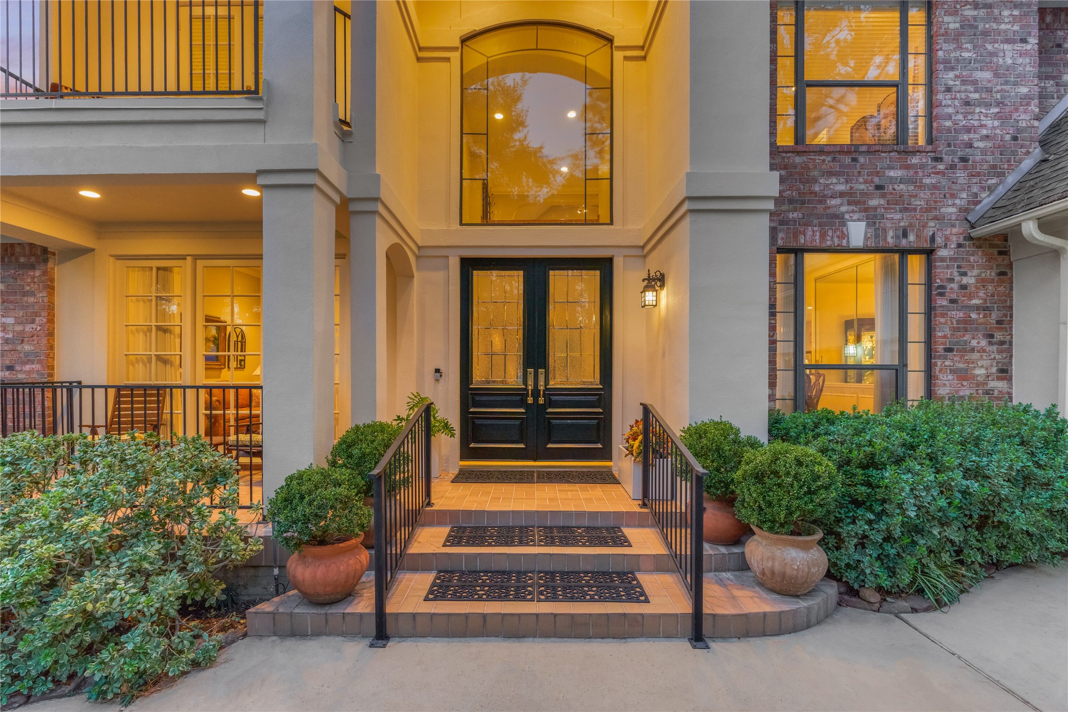 The stately double door entrance with beautiful foliage and landscaping adds to the luxurious welcoming appeal of this home.