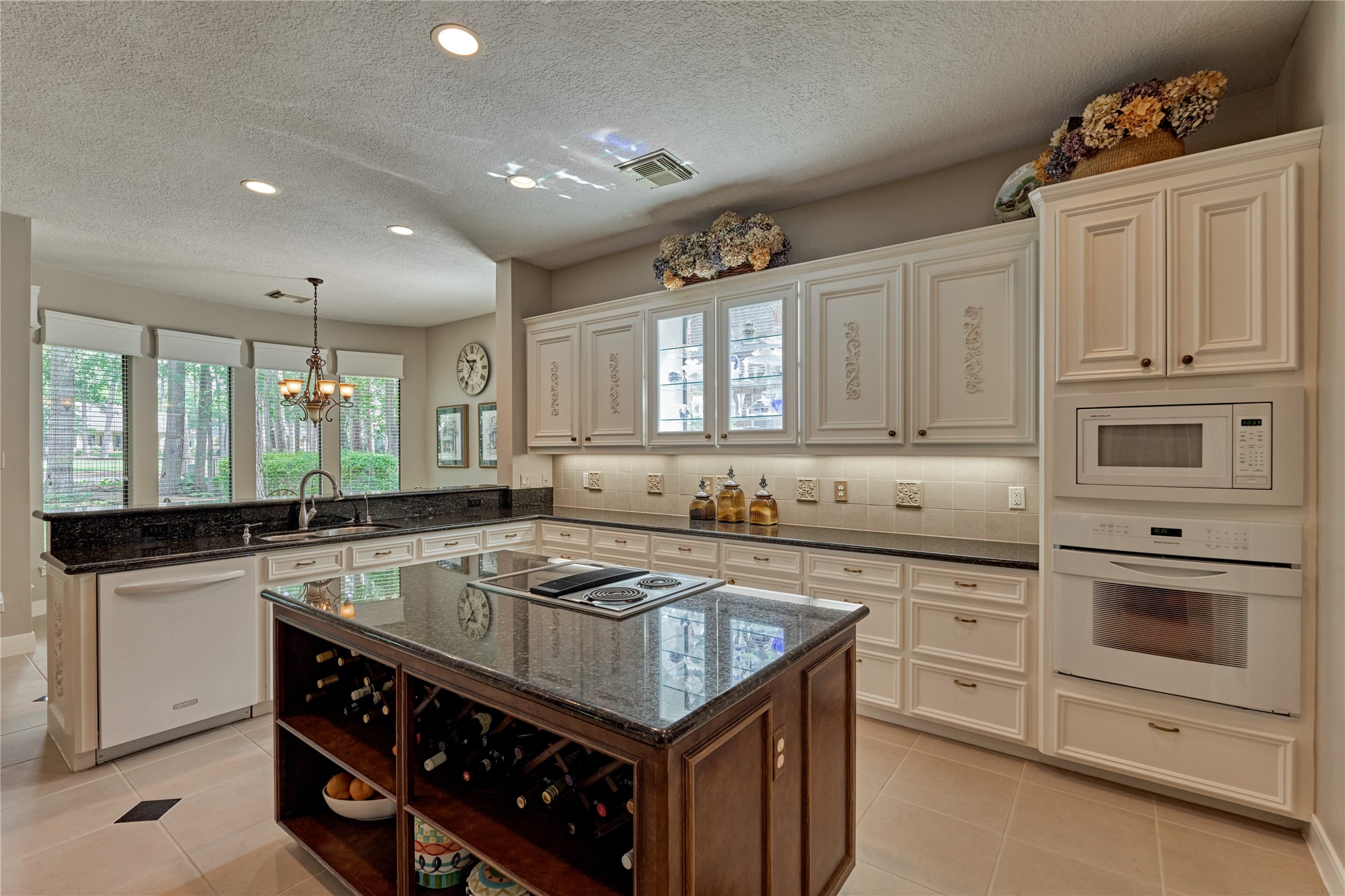 The center island houses a cooktop/oven and also has built-in wine storage. The second oven is built into the wall just below the microwave.