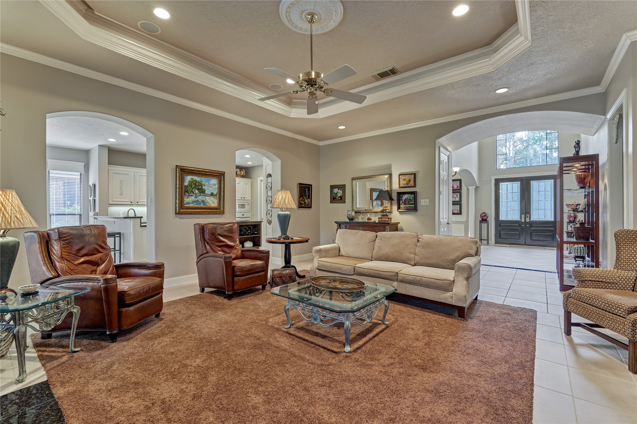 The inviting living room enjoys a warm fireplace and overlooks the backyard. The recessed ceiling provides a sophisticated aesthetic and elegantly illuminates the space.