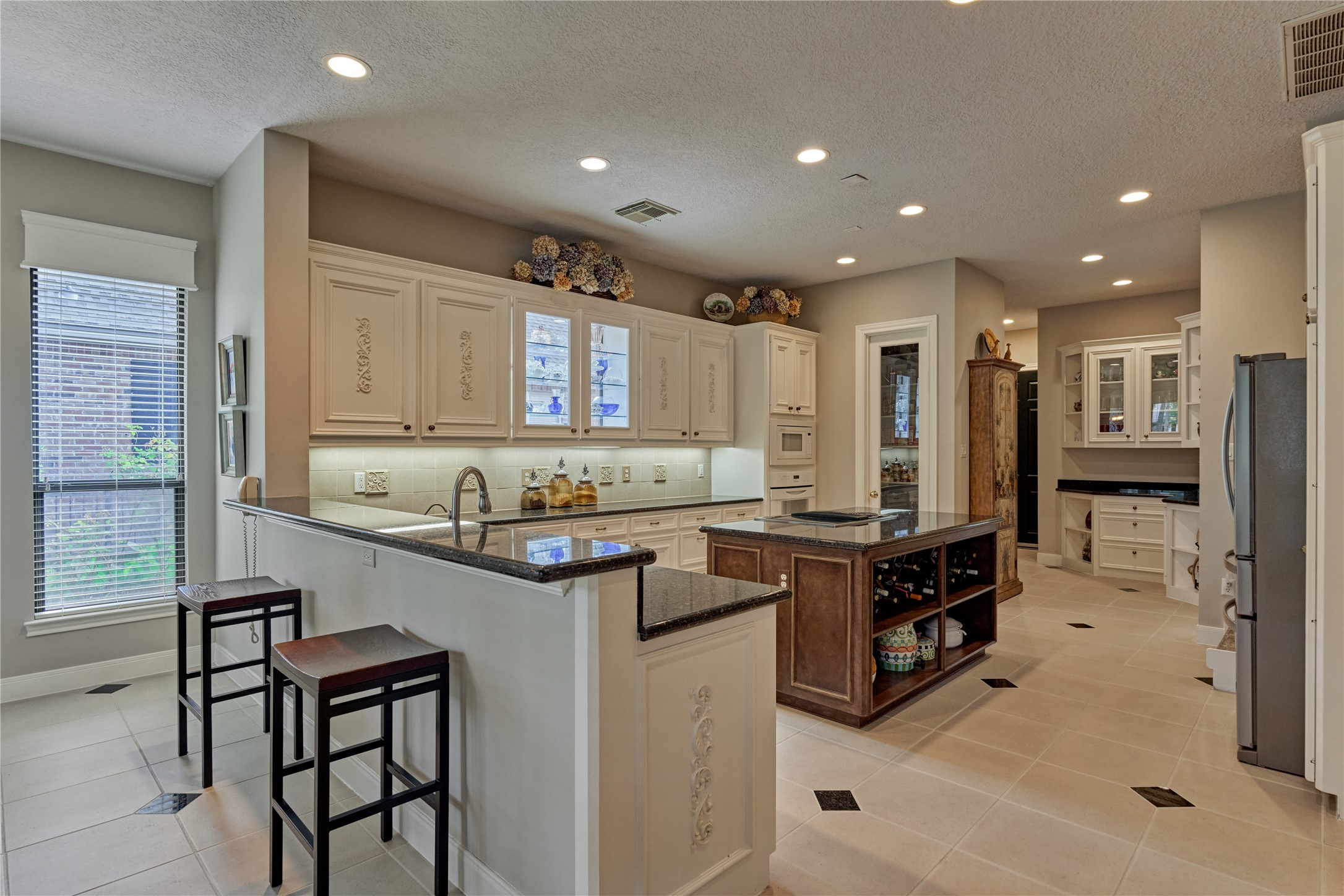 The elegantly appointed kitchen boasts of custom cabinetry featuring lighted glass uppers and a butler's pantry.