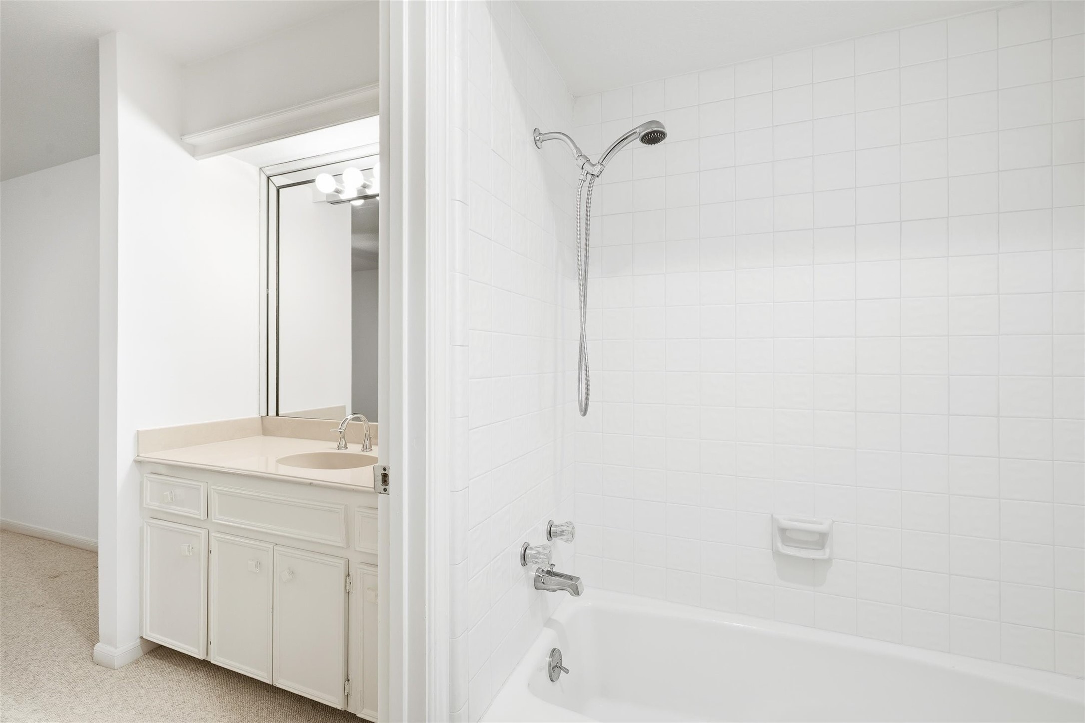 Bright bathroom with a sleek white tile shower and a practical vanity with ample storage, perfect for modern living.