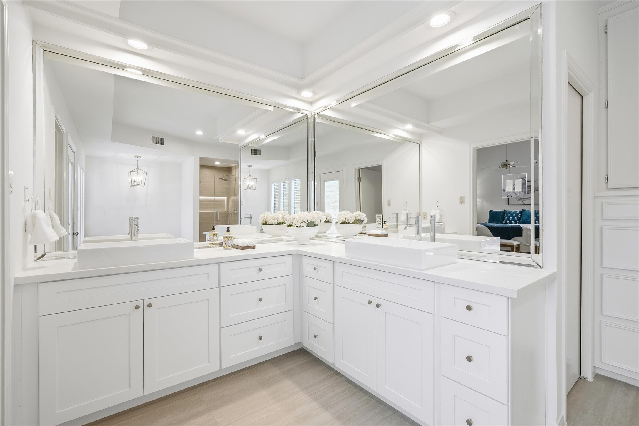 Luxurious bathroom featuring an expansive double vanity with elegant white cabinetry, sleek countertops, and large mirrors, creating a bright and inviting space.