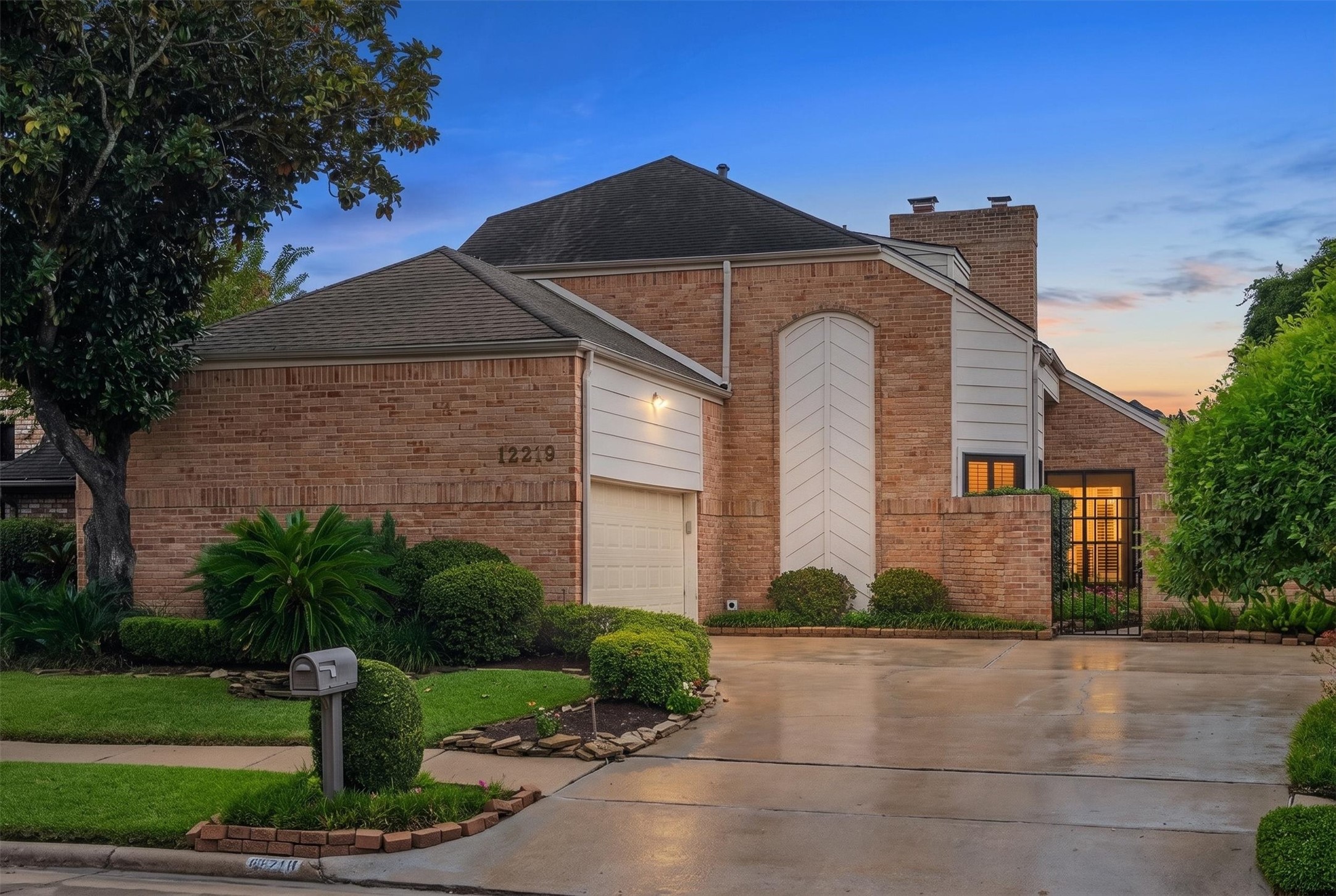 Stunning brick home with unique architectural features, surrounded by lush landscaping and a well-maintained driveway.