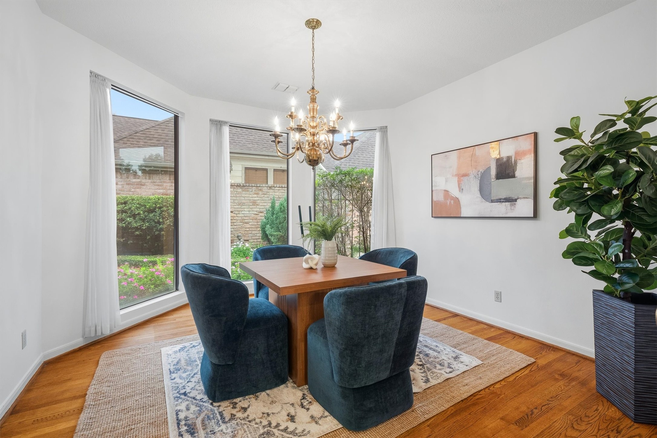 Elegant dining room with large windows offering abundant natural light, featuring a sophisticated chandelier.