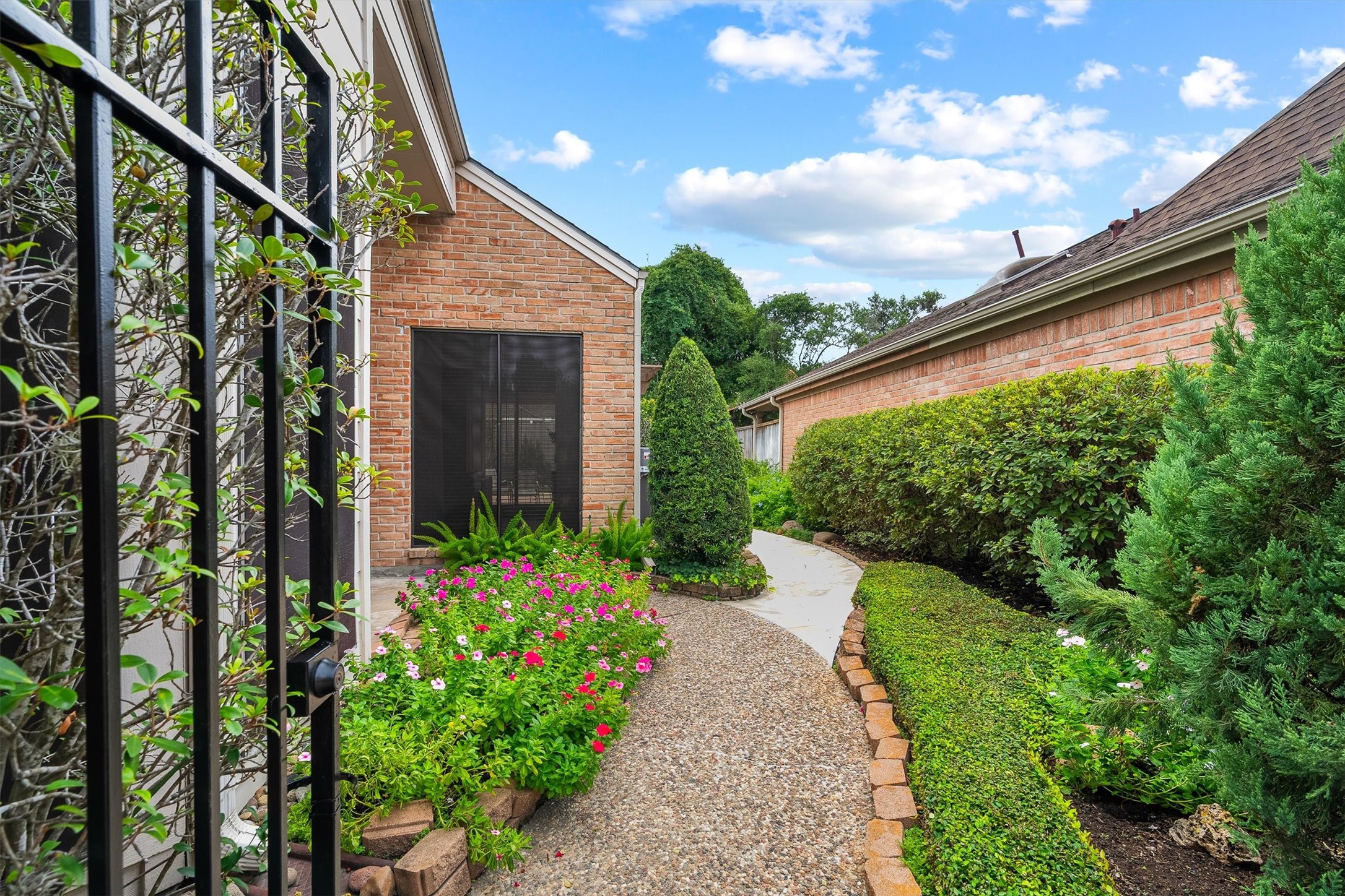 Nice pathway leads through a beautifully landscaped garden with vibrant flowers and lush greenery, enhancing the homes inviting brick exterior.
