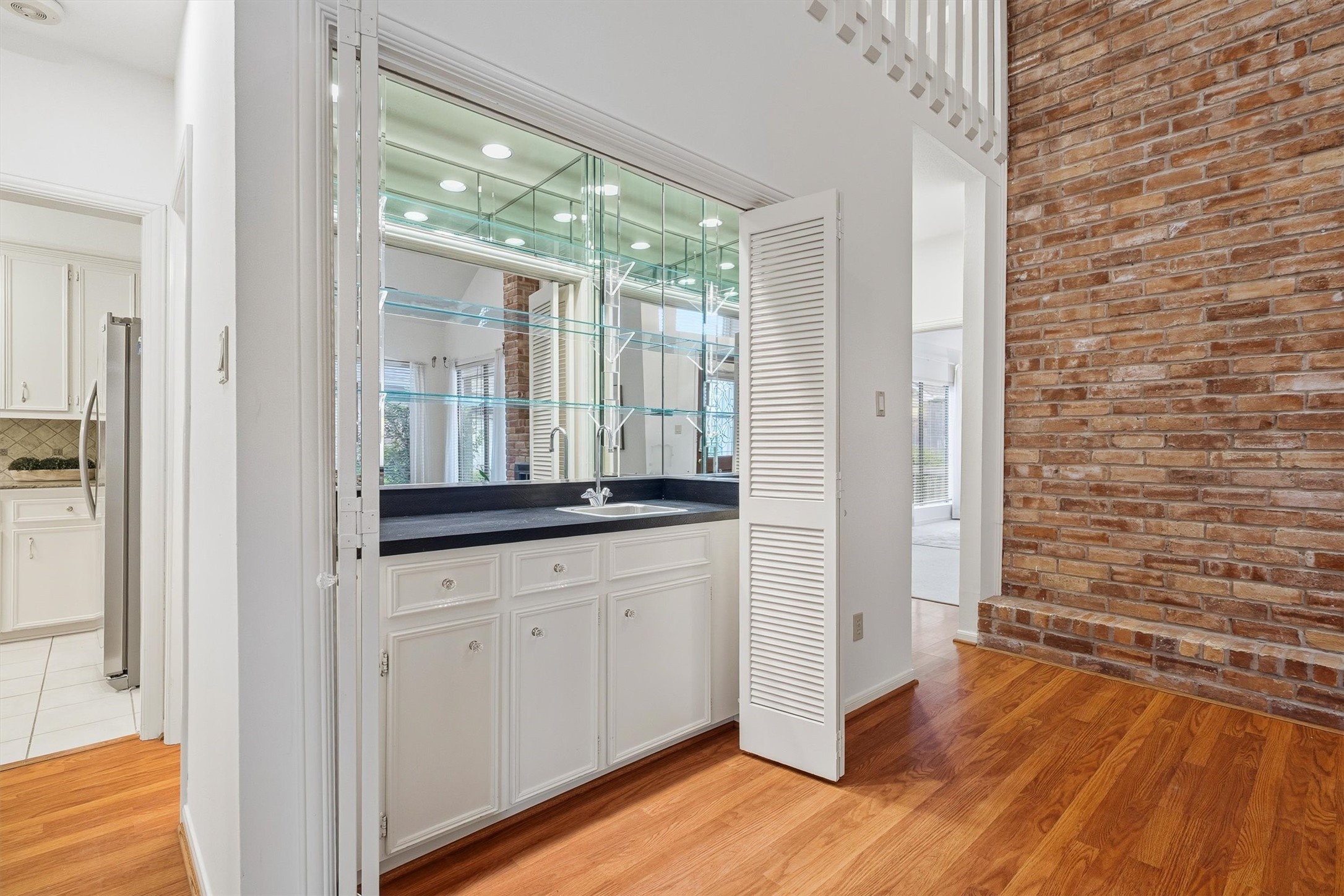 Elegant wet bar with sleek cabinetry and mirrored shelving, perfect for entertaining in style.