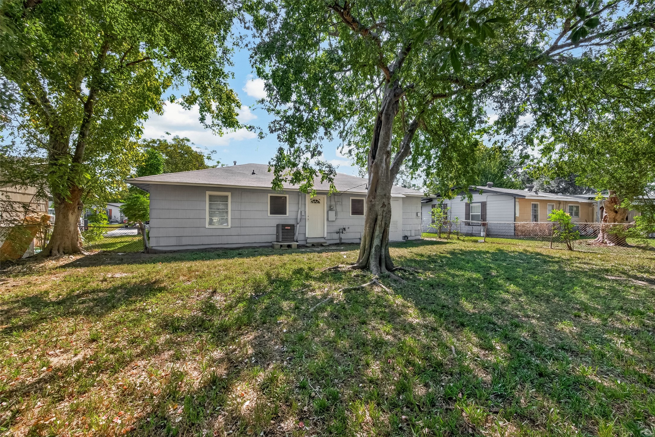 Backyard with large shade trees and open lawn.