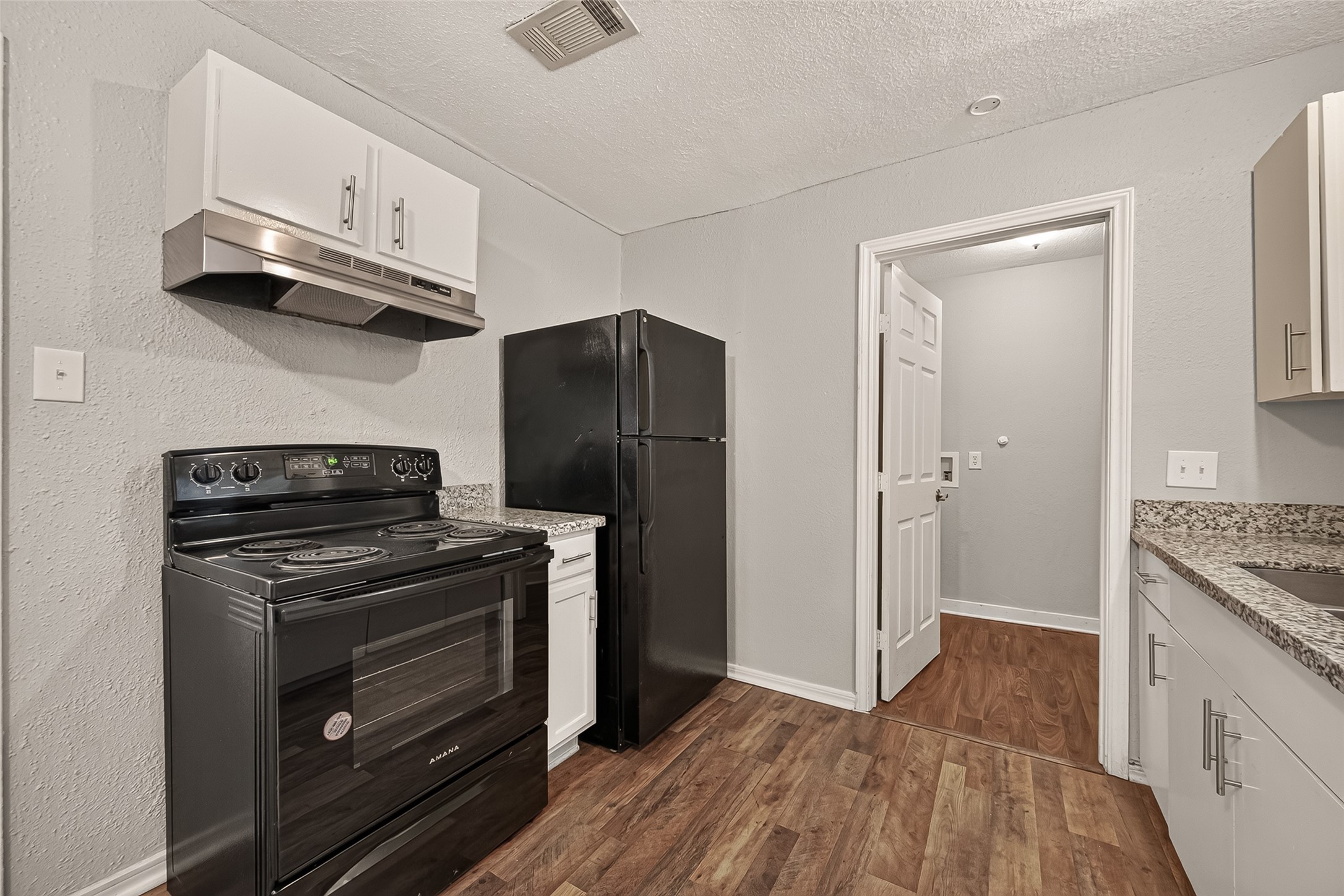 Kitchen with granite countertops, black appliances, and access to the utility room.