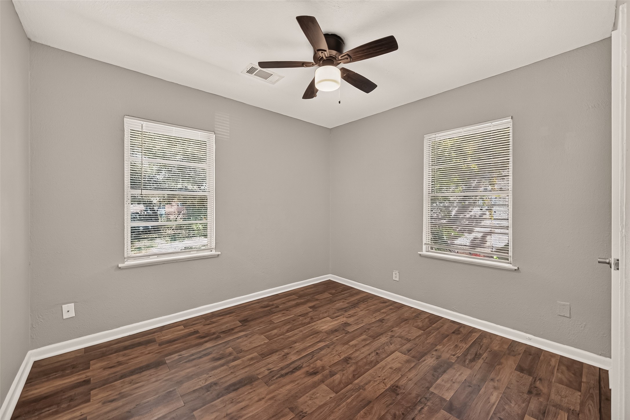 Bedroom 2, unfurnished, with windows on two walls and ceiling fan.