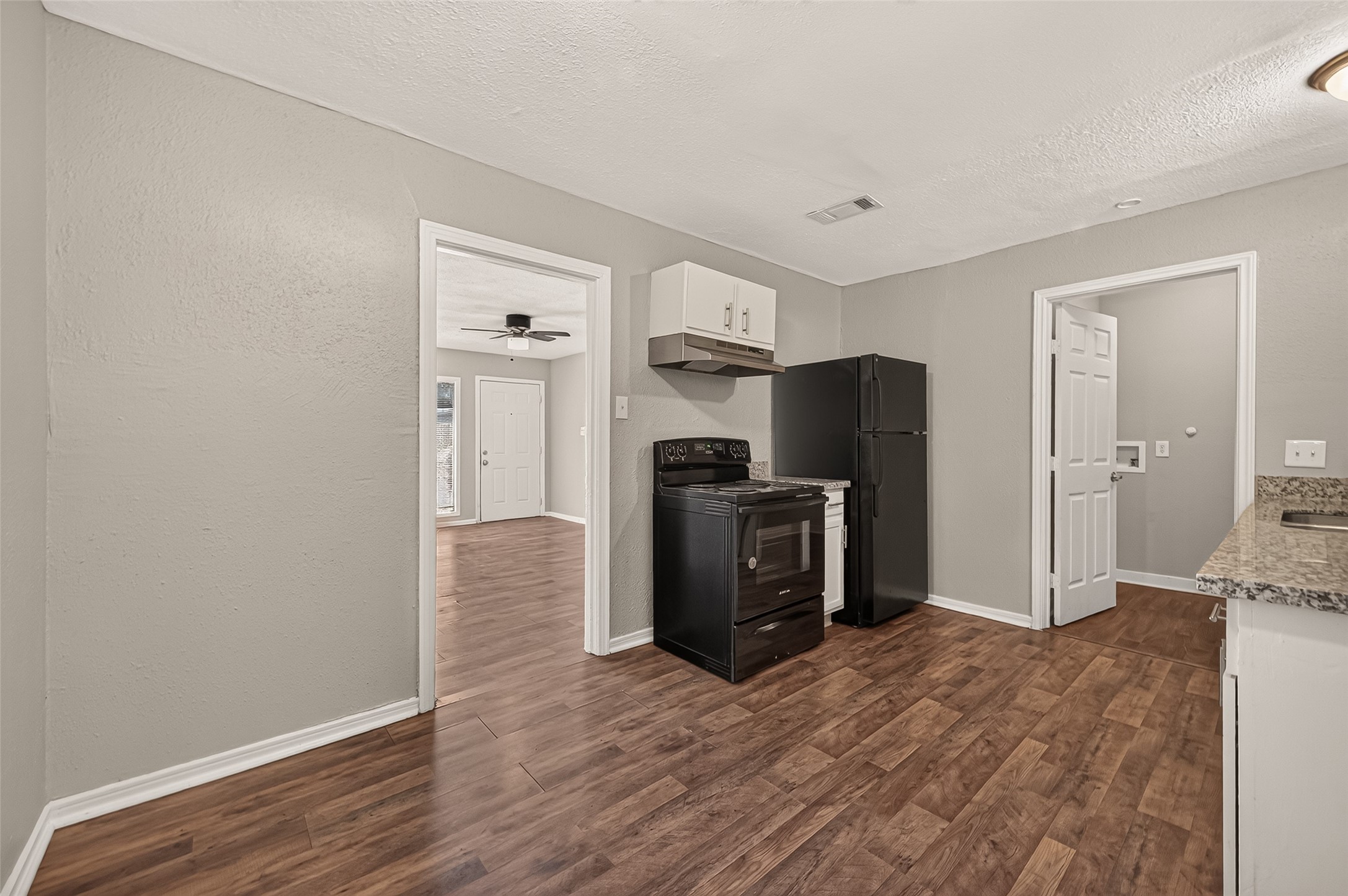 Kitchen with refrigerator and range, with view through to the living room.