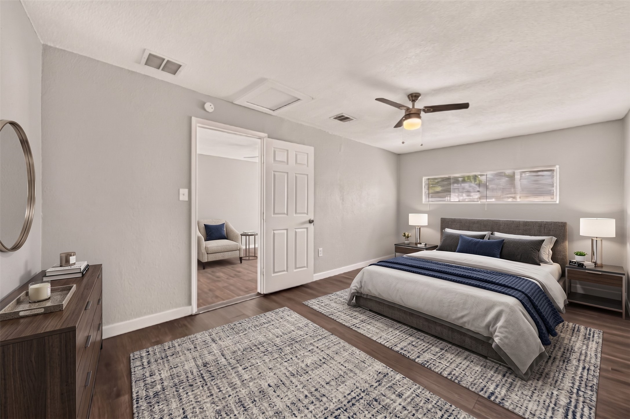 Primary bedroom with ceiling fan, clerestory window, and door to the en-suite bath. (Virtually staged)
