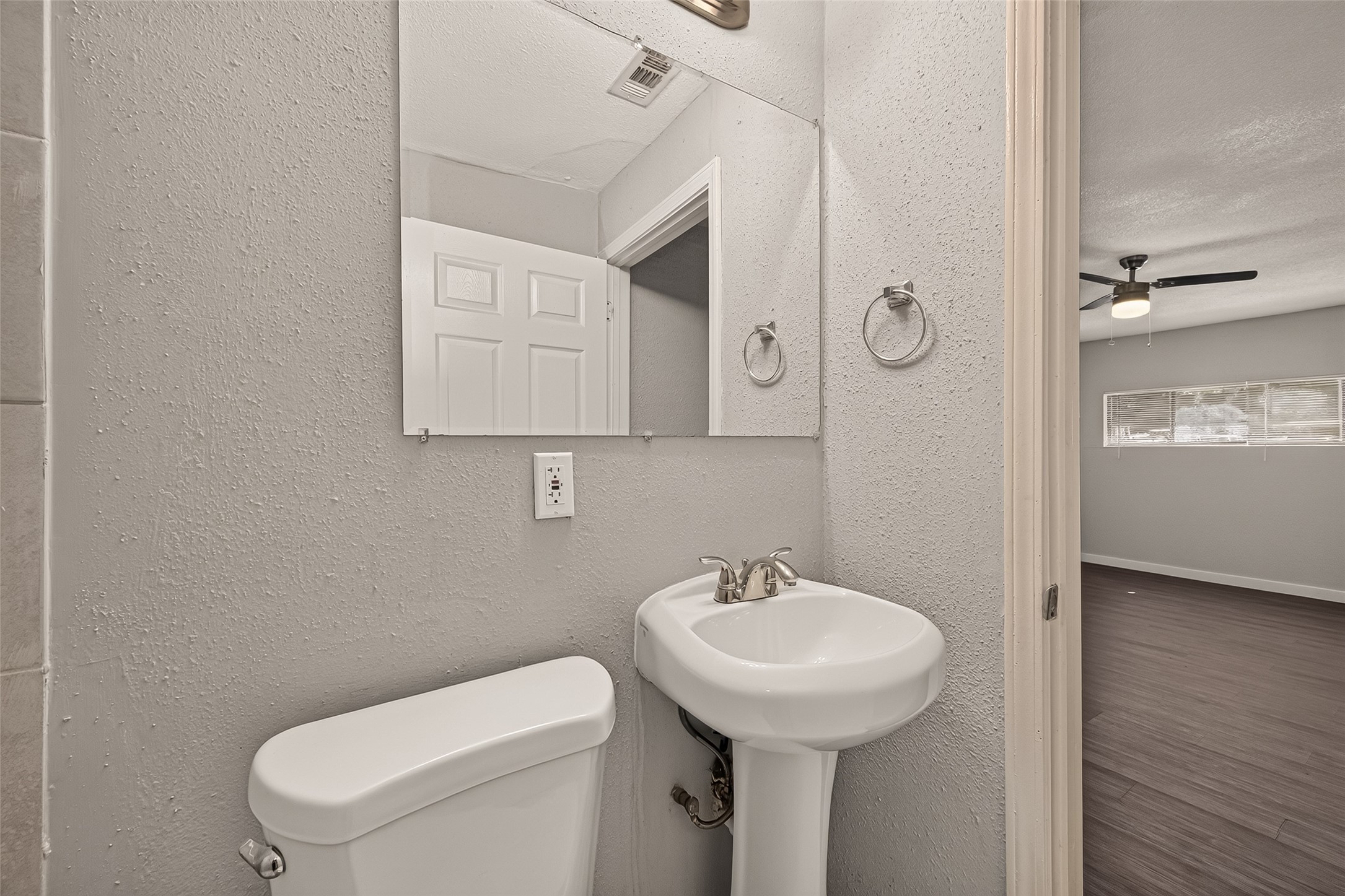 Primary en-suite bath with tile flooring and pedestal sink, open to the primary bedroom.