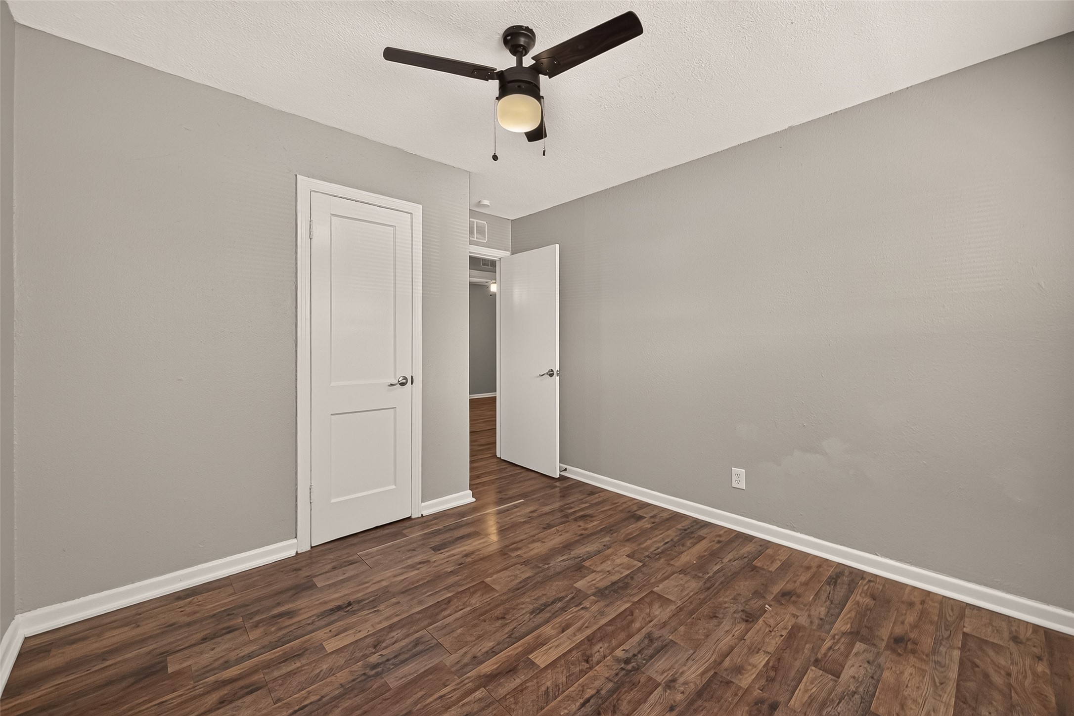 Bedroom 3, unfurnished, with ceiling fan and door to the hall.