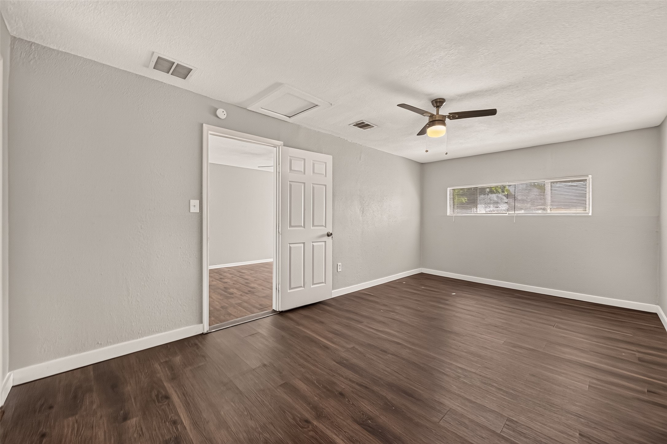 Primary bedroom, unfurnished, with ceiling fan and clerestory window.