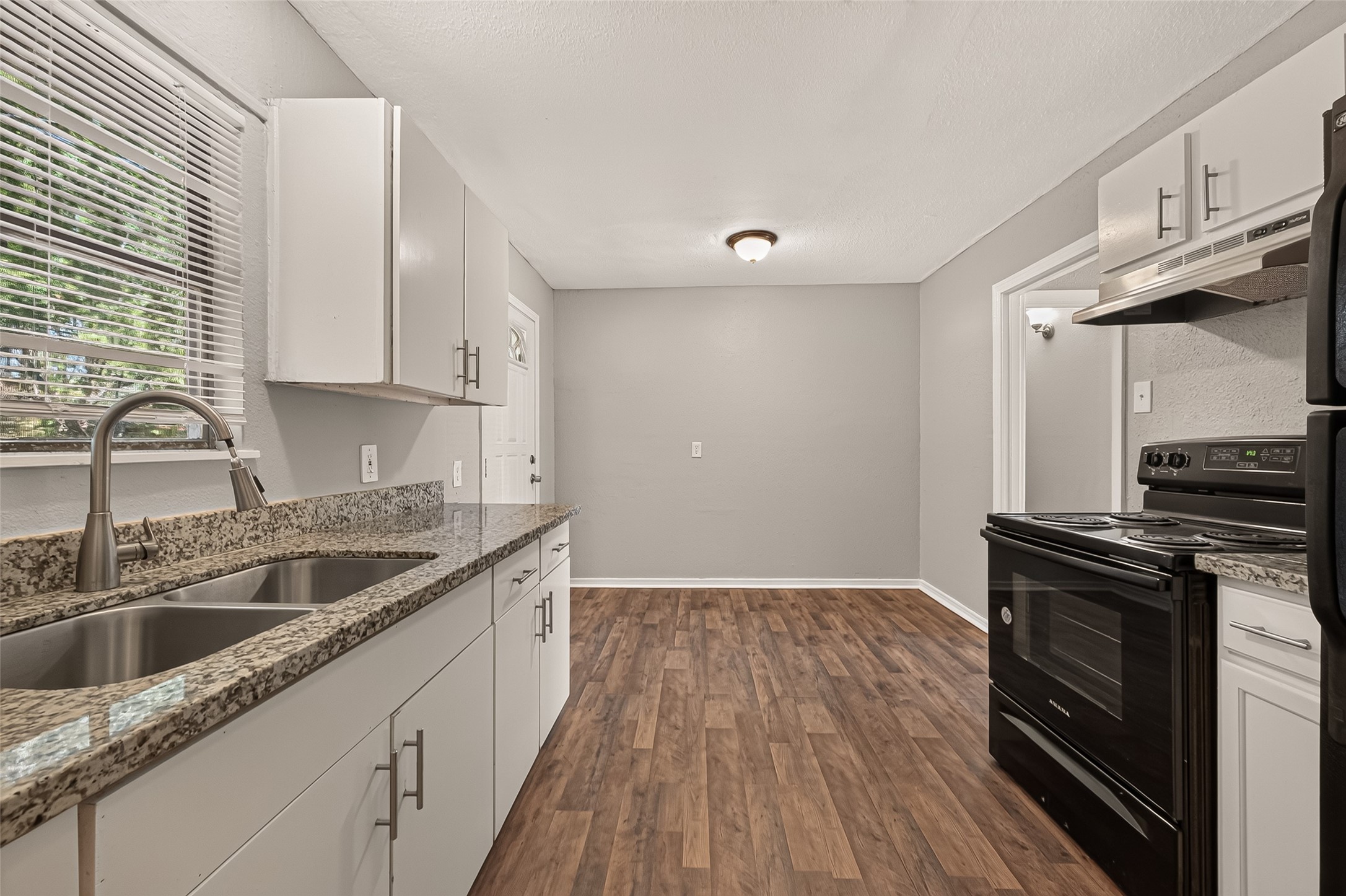 Kitchen, unfurnished, with granite countertops and view to the eat-in area.