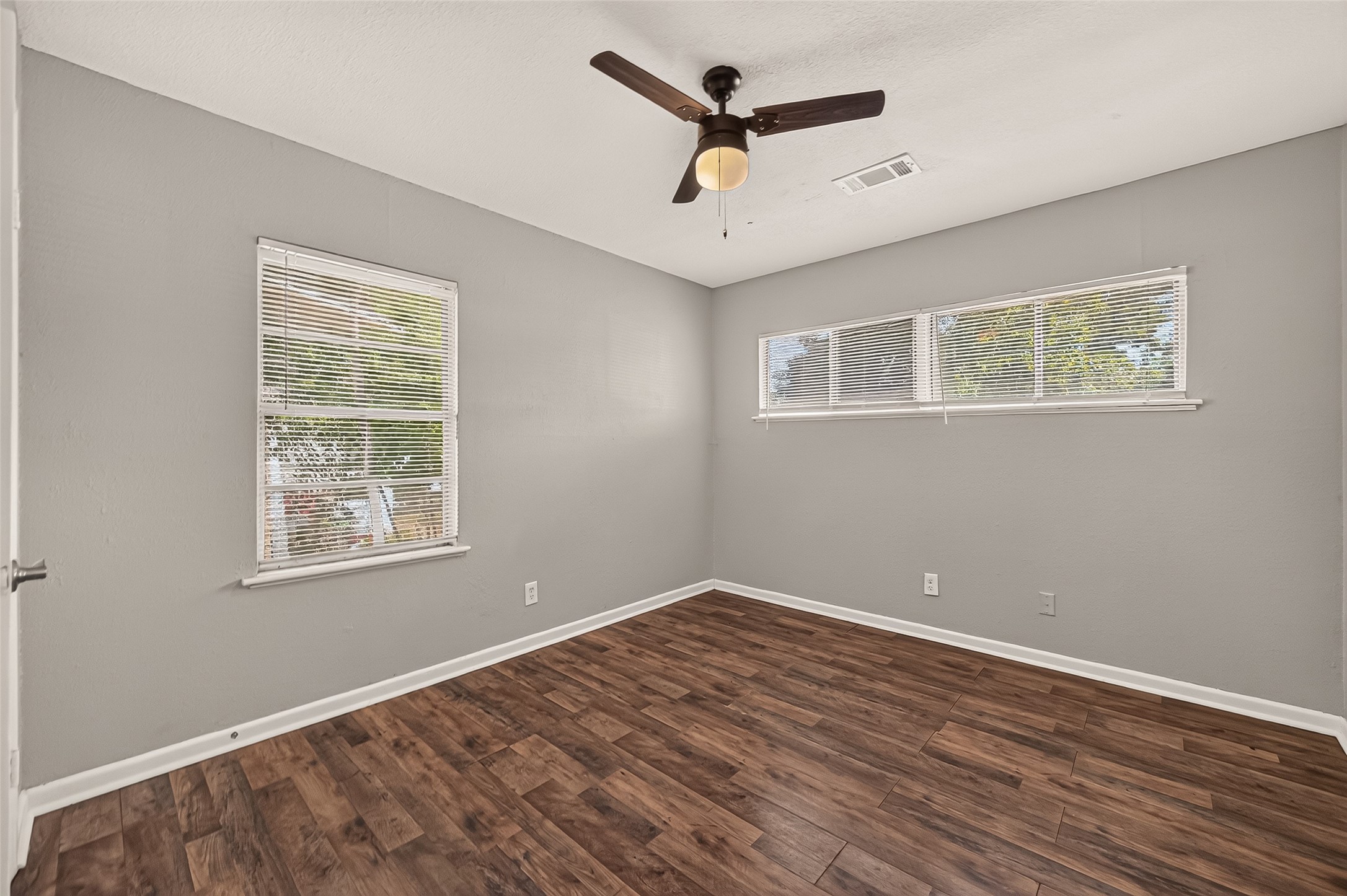 Bedroom 4, unfurnished, with two windows and ceiling fan.
