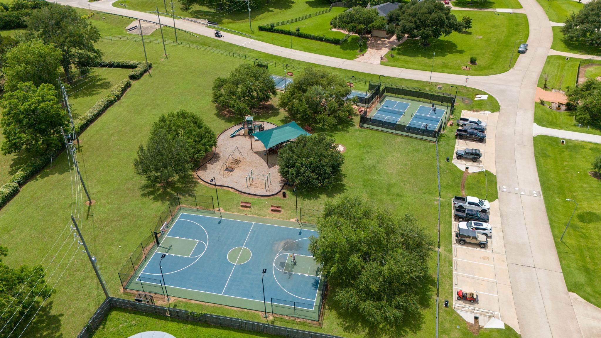 This view showcases another fantastic area of the Weston Lakes community, featuring four pickleball courts, a sport court for basketball, and a playground. With an abundance of recreational amenities throughout the neighborhood, there is always something fun to enjoy for residents of all ages.
