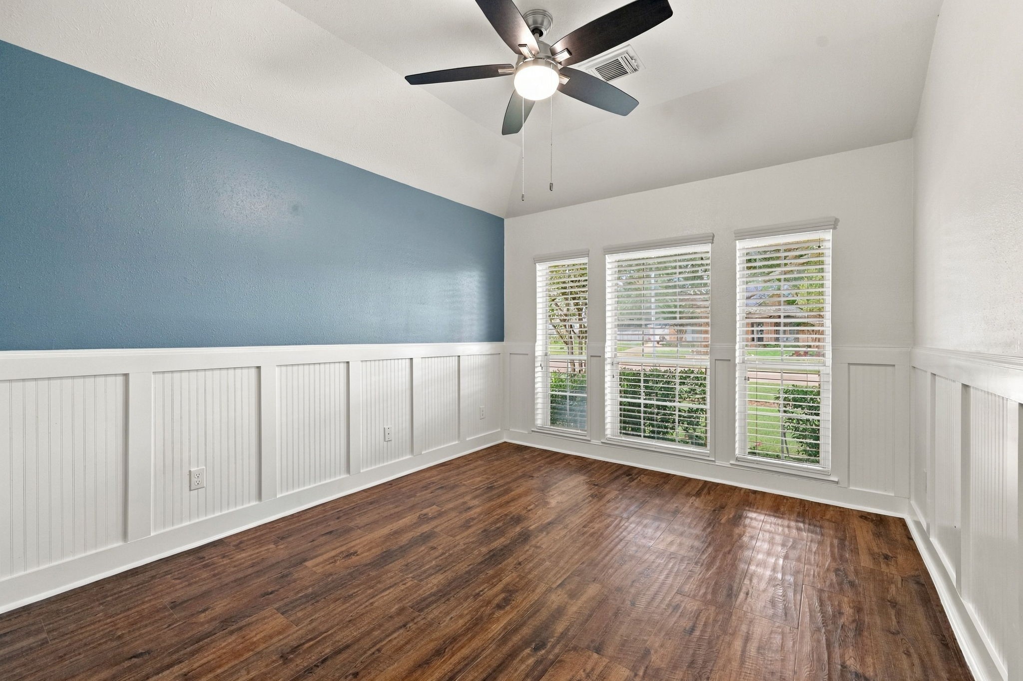 All Secondary Bedrooms are generously sized and feature walk-in closets and gorgeous wood-look tile flooring. This Bedroom located at the front of the home, offers charming details including wainscoting, an accent wall, and a 5-blade ceiling fan. Three windows with 2-inch blinds provide an abundance of natural light and beautiful views of the front yard.