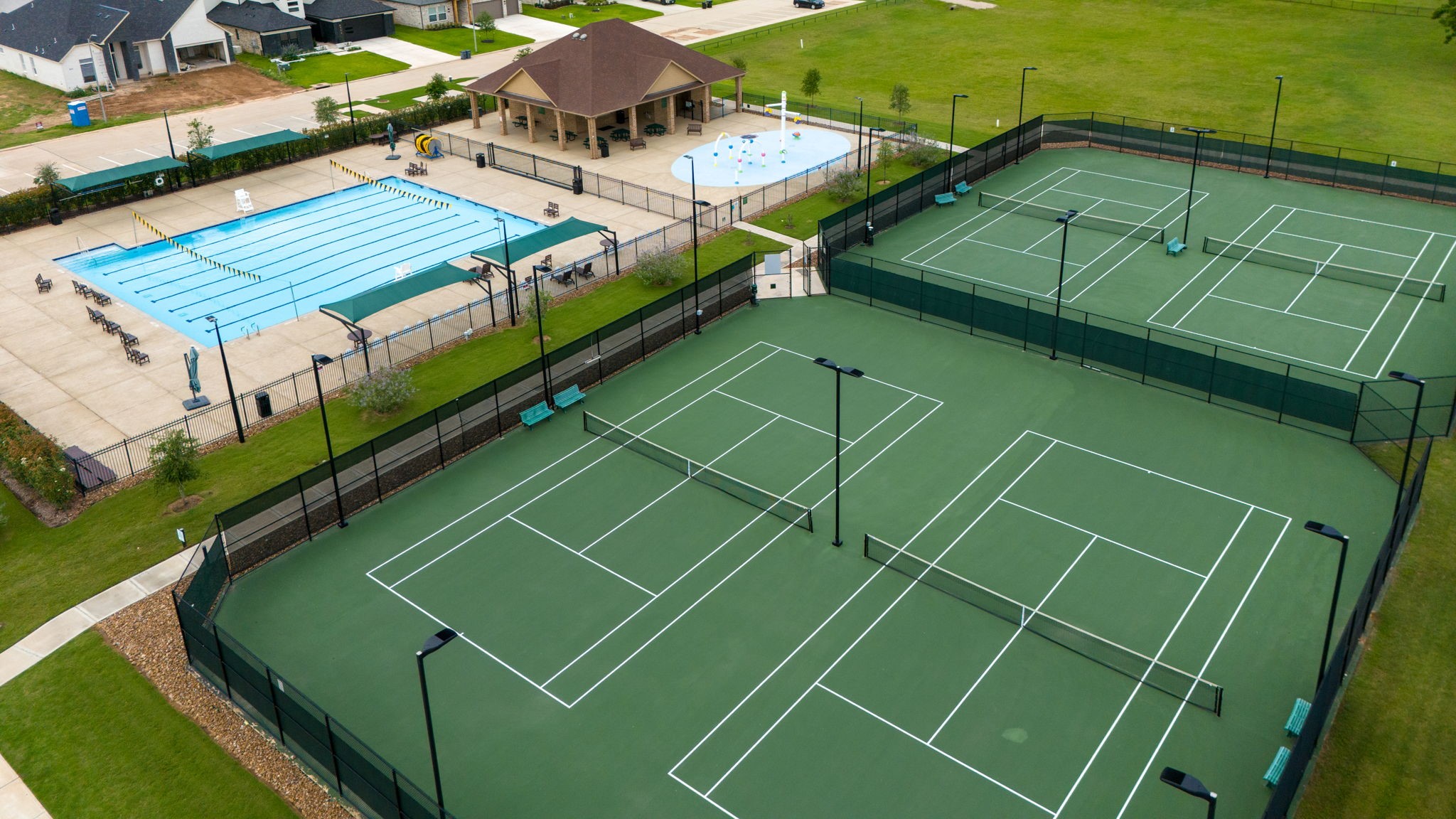 Weston Lakes is a resort-style community offering an abundance of amenities to keep you active and entertained. This photo showcases The Park Recreational Complex featuring 4 tennis courts and one of the communitys two Olympic-size swimming pools, providing residents with exceptional opportunities for recreation, fitness, and relaxation.