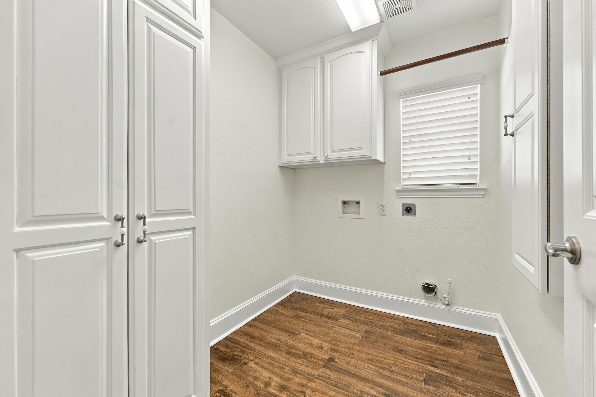The Laundry Room is conveniently located just to the right of the Dry Bar and features a built-in ironing board, abundant storage cabinetry, and both gas and electric connections for your choice of dryer. A window with 2-inch blinds provides natural light, creating a bright and functional workspace.