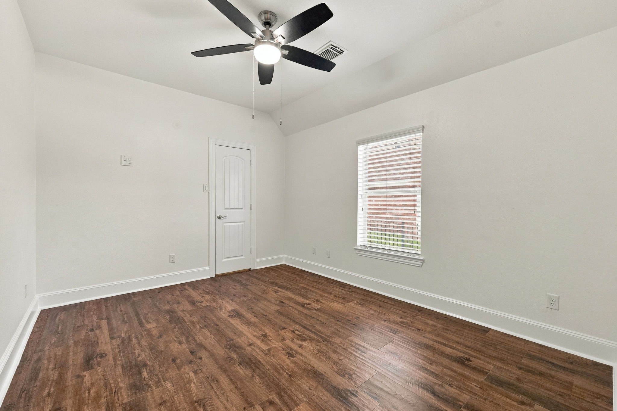 This Secondary Bedroom offers beautiful wood-look tile flooring, a convenient mid-wall TV outlet for easy TV installation, a spacious walk-in closet, a window with 2-inch blinds that provides natural light, and a 5-blade ceiling fan for added comfort.