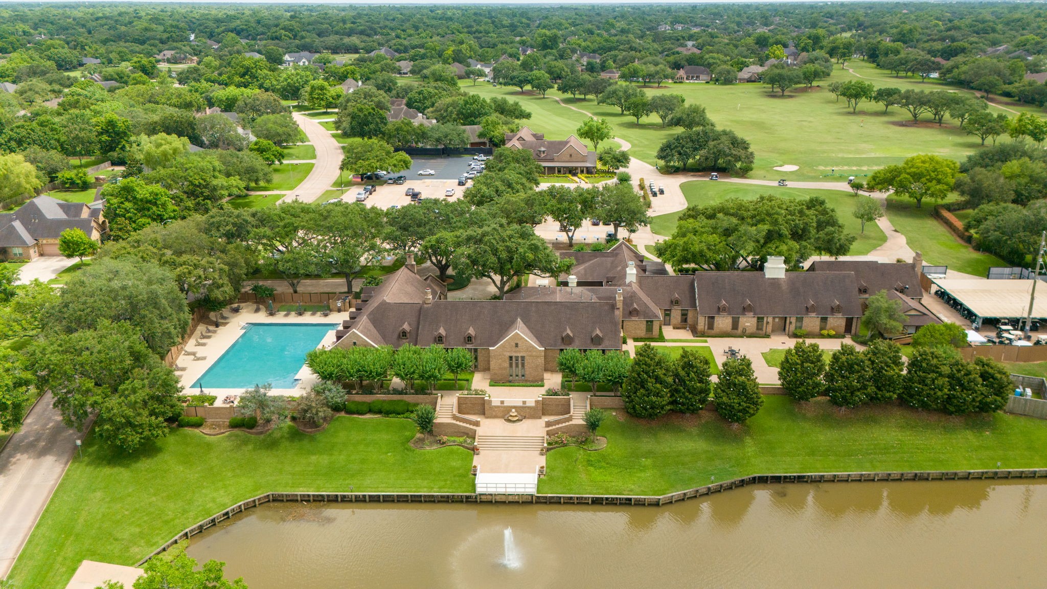 This view showcases the beautiful Weston Lakes Country Club and Waterside Grill, with the golf pro shop and scenic 18-hole golf course visible in the distance. The golf course meanders throughout the community, offering a beautiful setting for enjoying a round of golf. Residents can enjoy golf for an additional fee or upgrade their membership to include golf privileges.