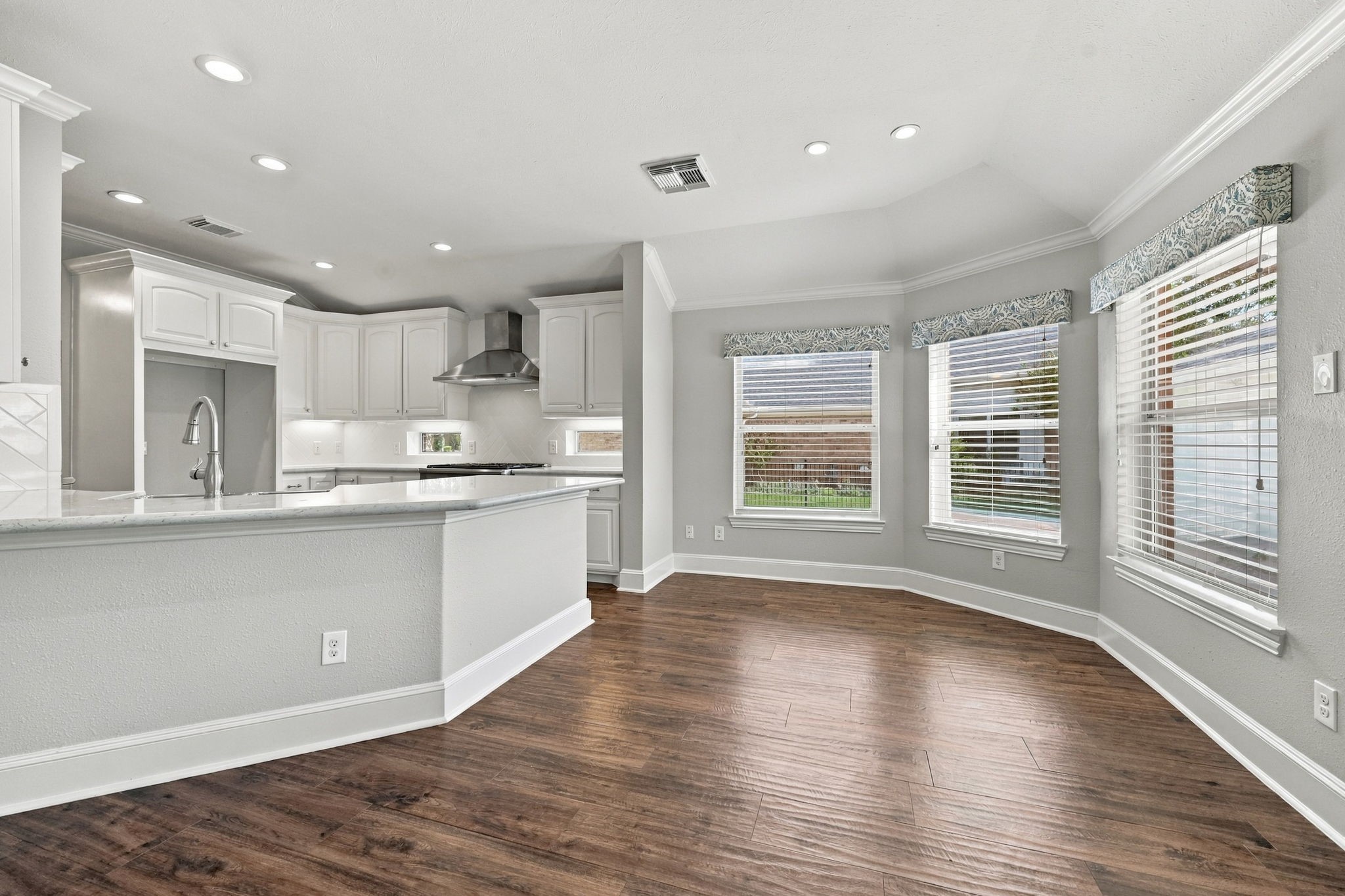 The Breakfast Area is elegant and inviting, featuring designer valances over three large windows with 2-inch blinds, beautiful wood-look tile flooring, and LED ceiling lighting. The abundance of natural light creates a bright and welcoming space for casual dining.