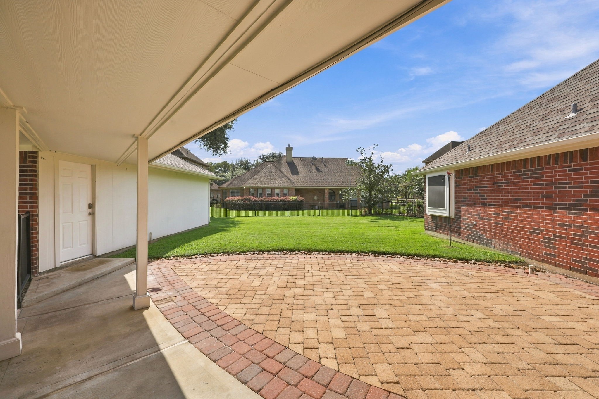 Lets step outside! This beautiful home is situated on an oversized 11,021-square-foot lot. This view showcases the covered breezeway connecting the detached garage to the home, providing convenient protection from the elements when bringing in groceries or heading to the house on a rainy day. The extended back patio features paver flooring and offers plenty of space for outdoor tables, chairs, and seating, creating an inviting setting for relaxing and entertaining.
