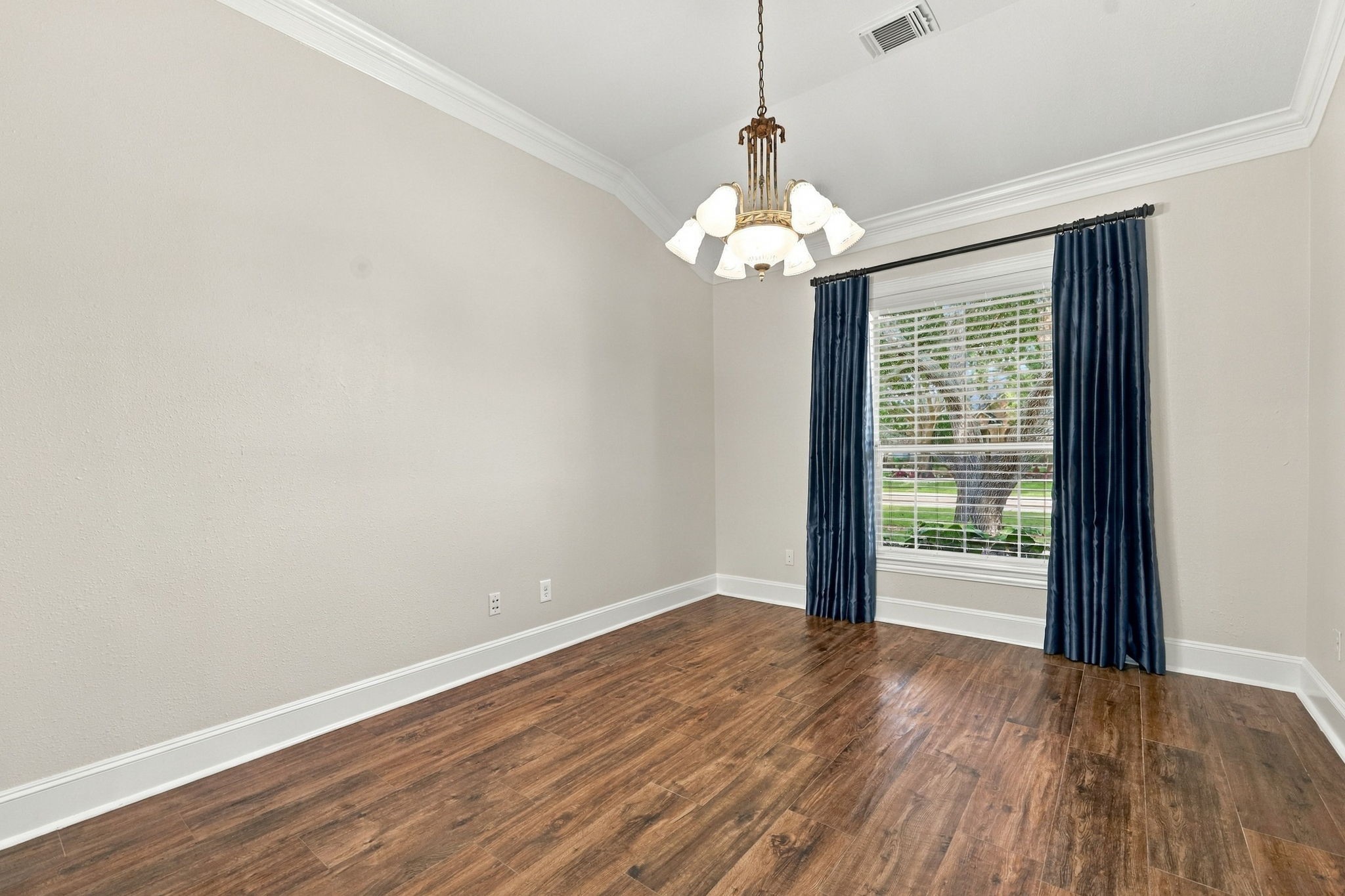 The Formal Dining area is located just off the Foyer and features elegant silk window drapes, a large picturesque window, beautiful wood-look tile flooring, and an elegant chandelier, creating a warm and sophisticated setting for entertaining and special occasions.