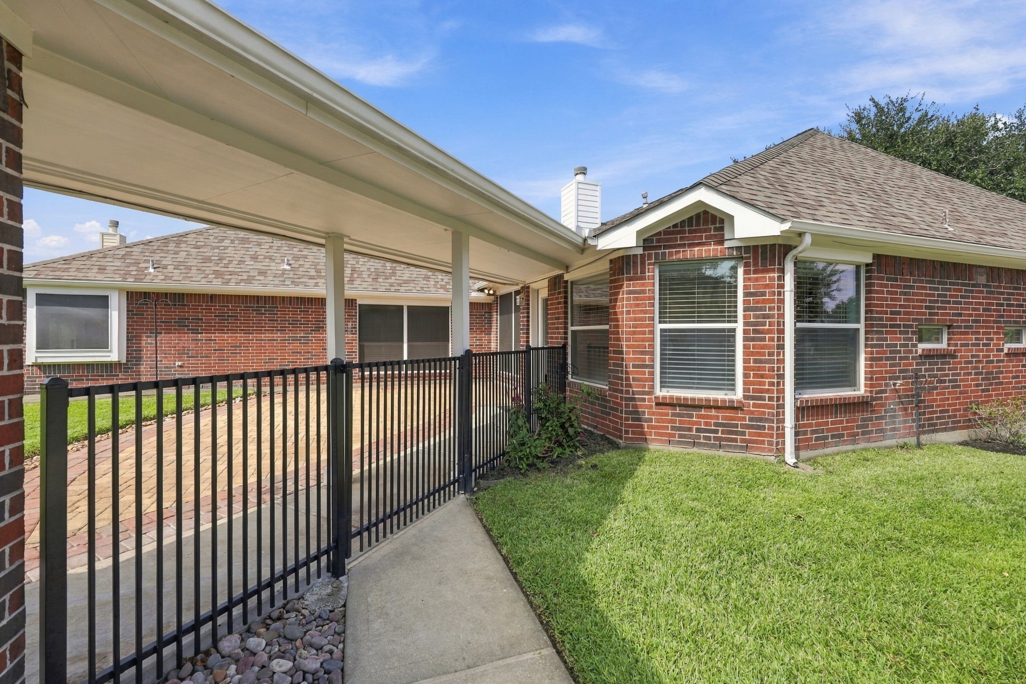 A closer look at the wrought-iron gate separating the driveway from the Backyard, providing an attractive touch while helping create a defined and private outdoor space.