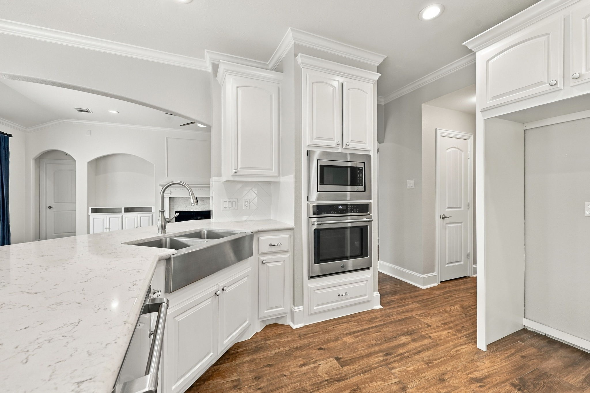 The refrigerator space is beautifully framed in for a polished, built-in look, while the door to the left leads to the spacious pantry, providing convenient access to additional storage.