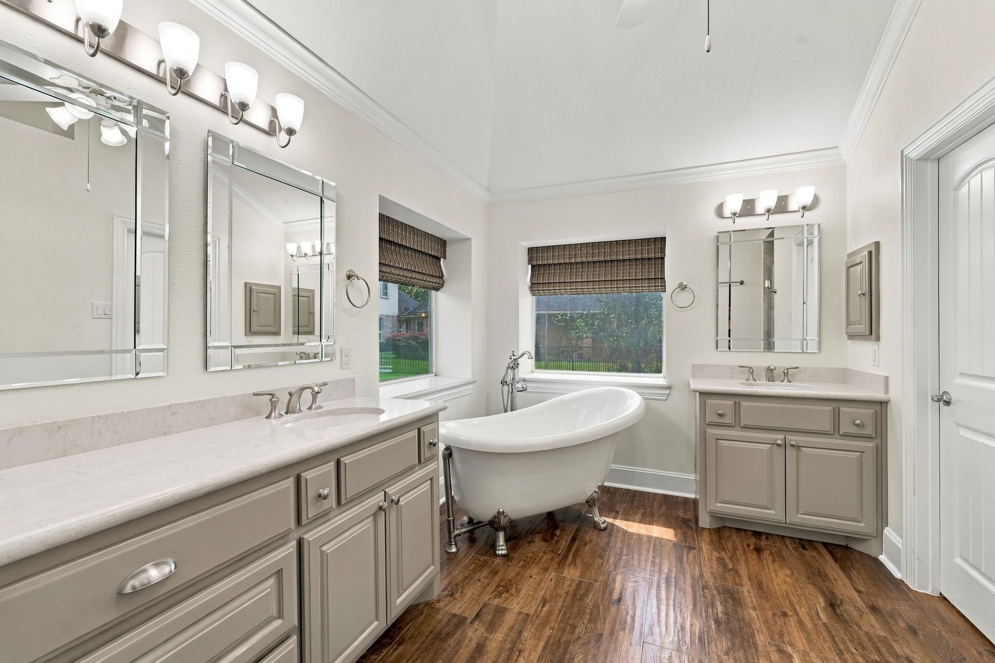 The Primary Bath is luxurious and beautifully appointed with wood-look tile flooring, dual vanities featuring beautifully painted accent cabinetry and drawers, medicine cabinets, beveled mirrors, a stunning freestanding clawfoot soaking tub, and gorgeous Quartz countertops. Thoughtfully designed finishes create a relaxing and sophisticated retreat.